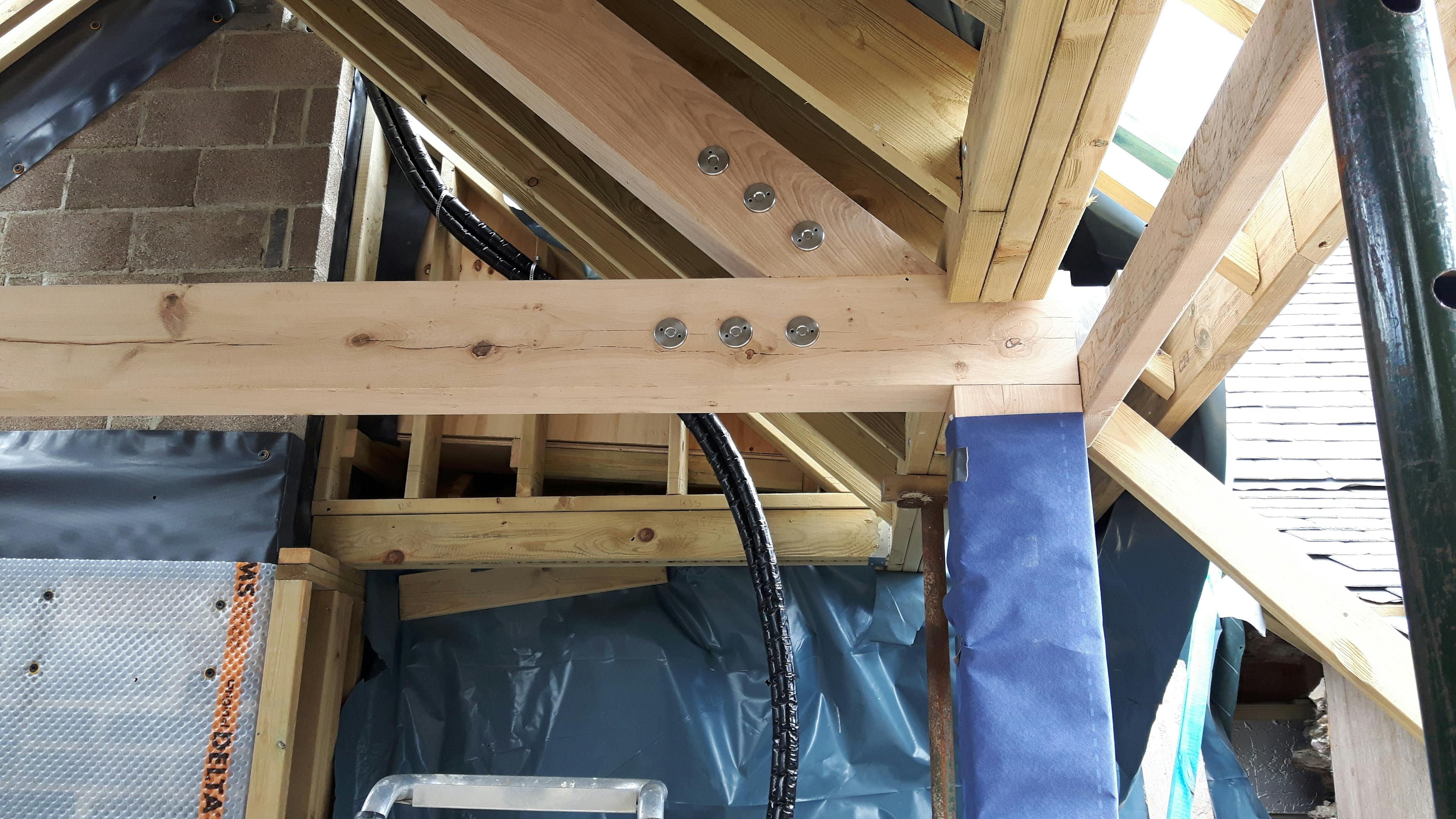 Oak-framed extension being wrapped and insulated, featuring visible steel pignut fixings