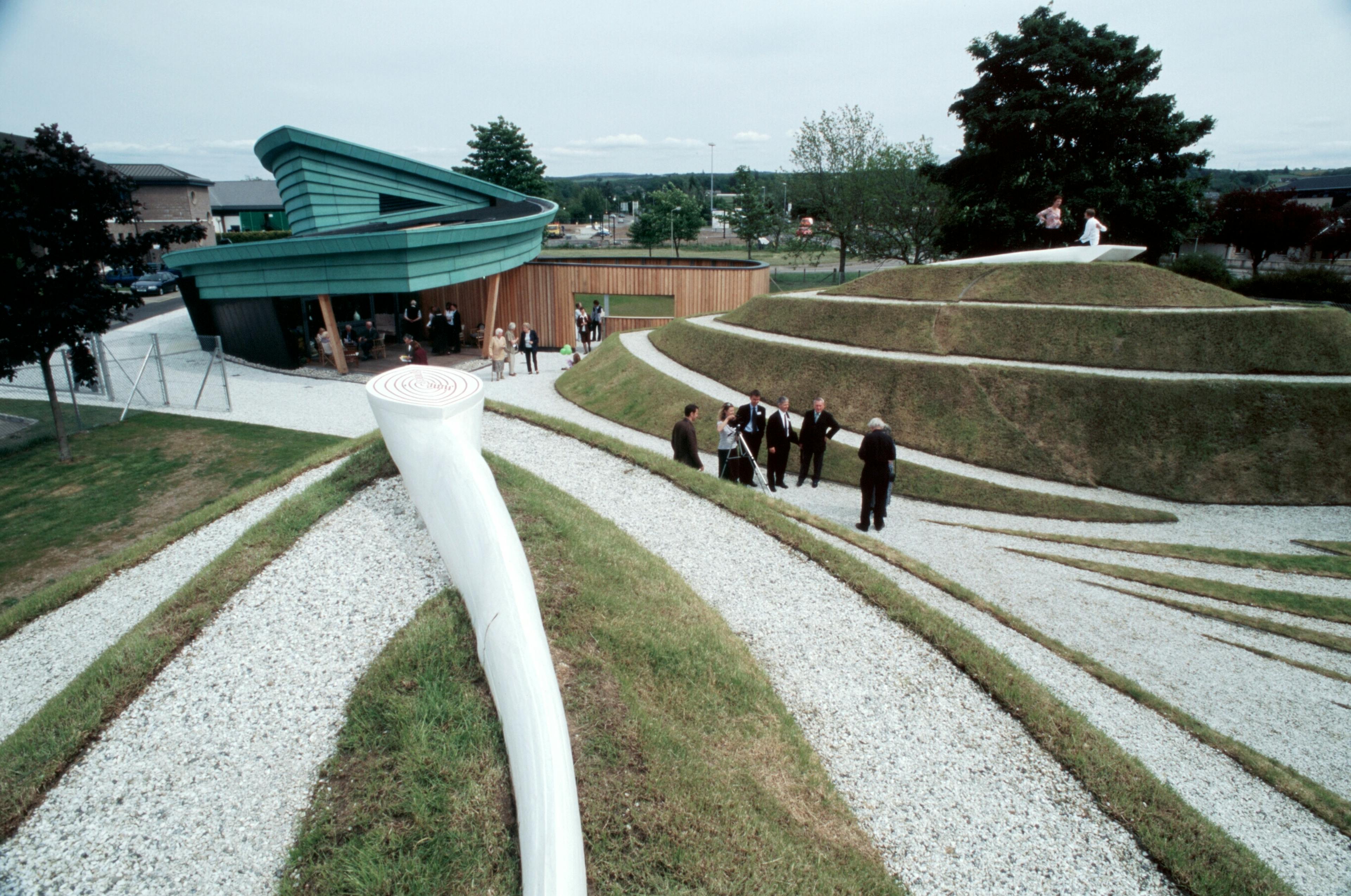 Tiered gardens surrounding the Maggie's Centre structure at Raigmore Hospital in Inverness, featuring landscaped greenery and tranquil seating areas