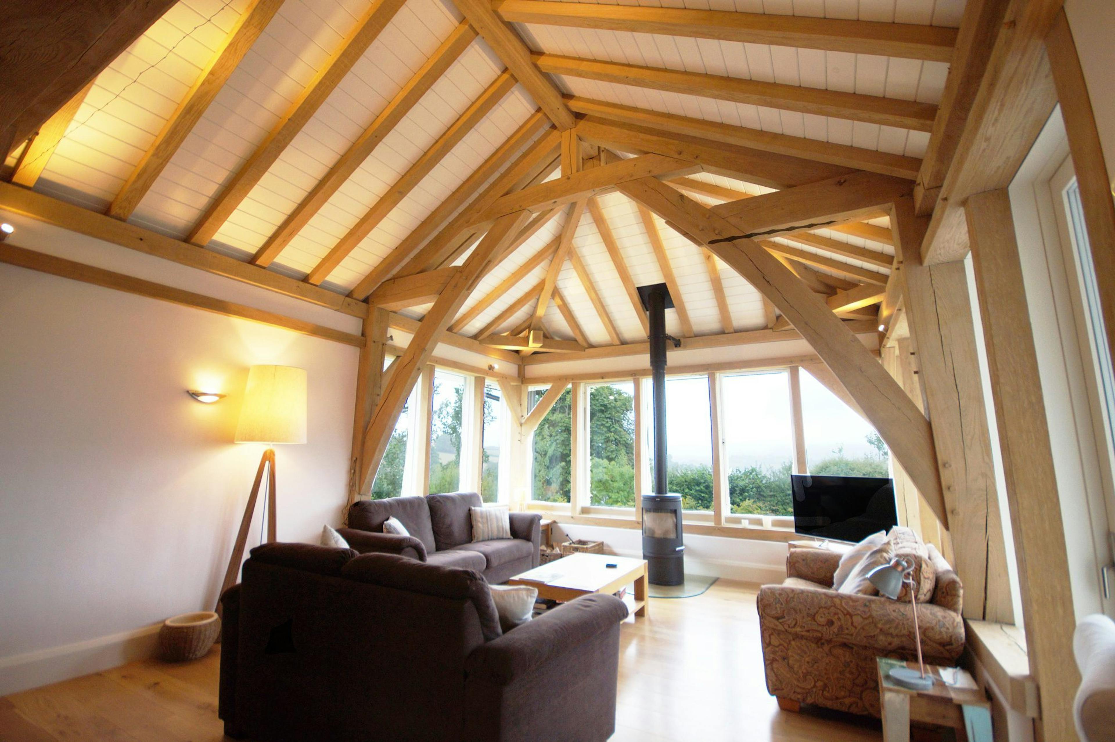 Interior view of a cosy living space within an oak-framed two-storey family home, featuring a central fireplace and painted softwood paneling