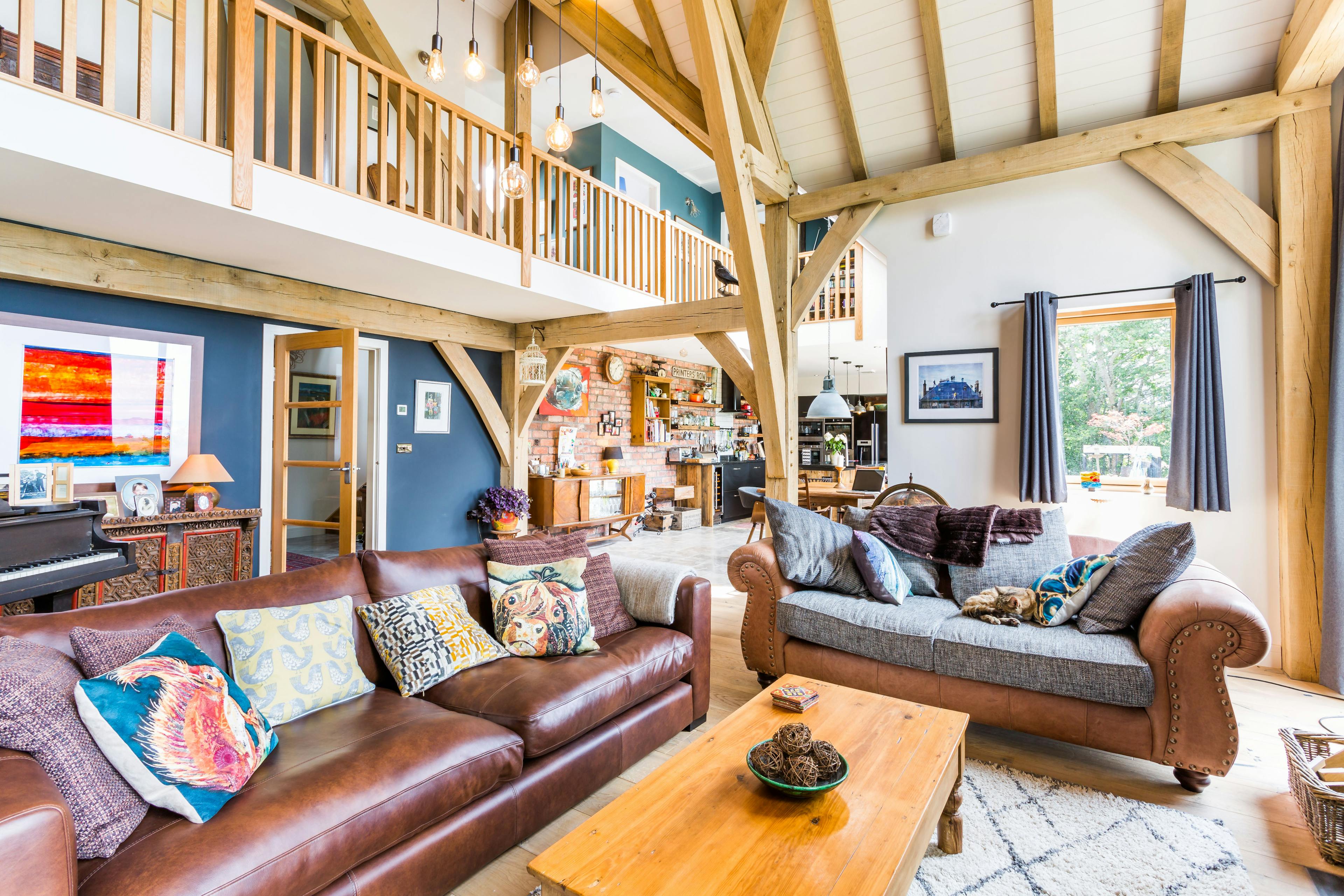 Internal view of an oak-framed living space with vaulted ceilings and a view overlooking the mezzanine