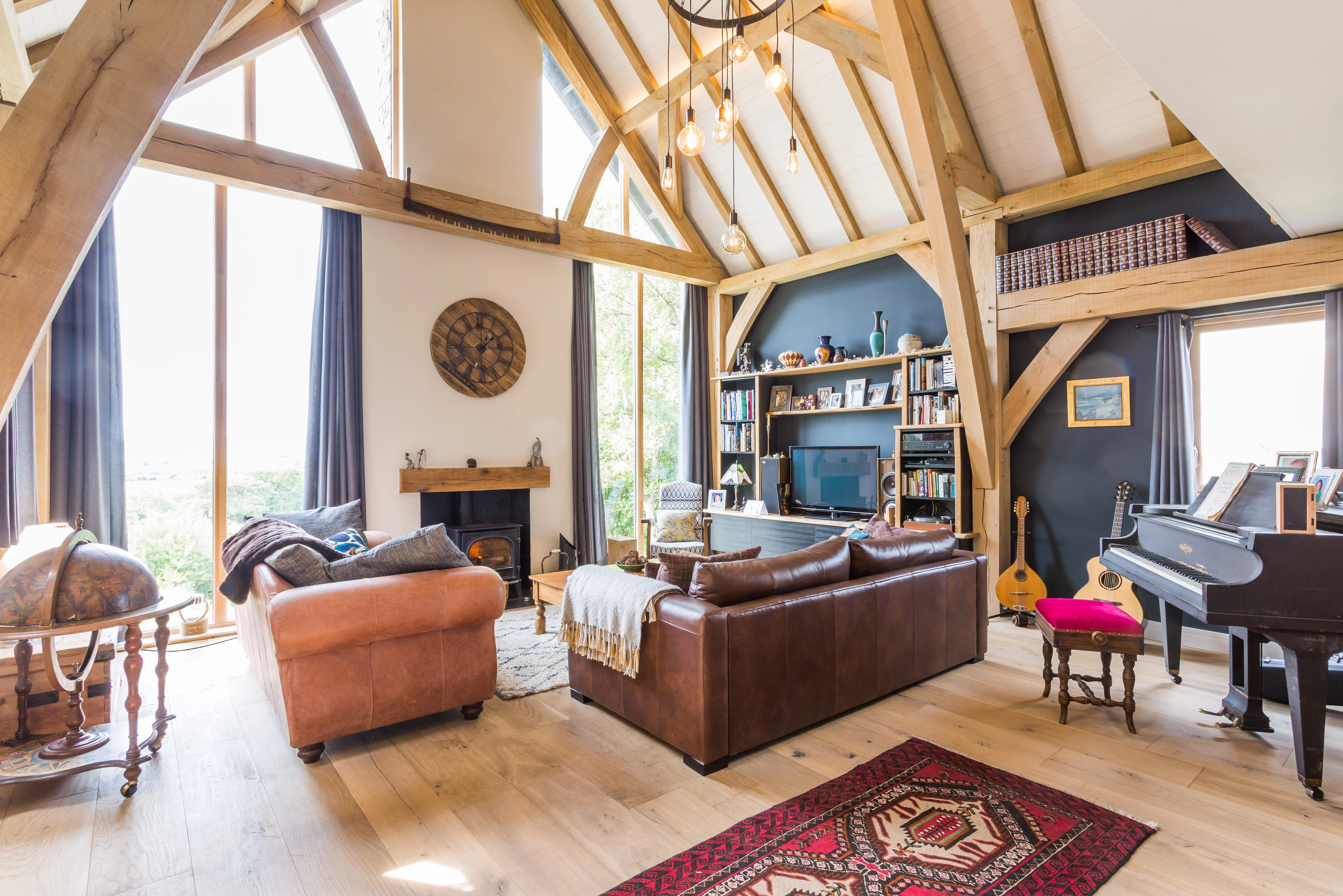 Vaulted oak-framed living space with a central fireplace and a striking glazed gable end