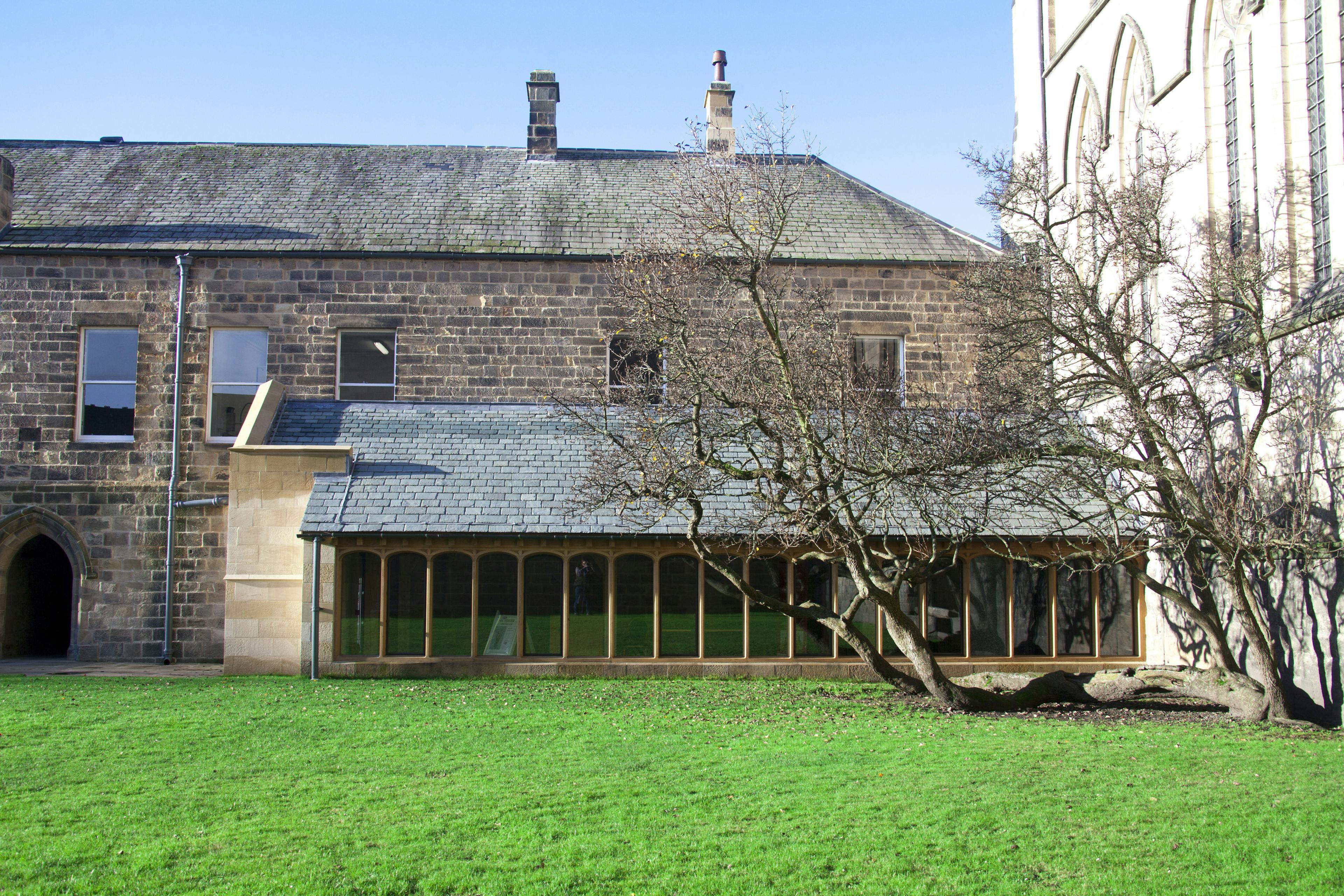 New oak-framed cloister at Hexham Abbey featuring arched framed windows, designed to complement the historic aesthetic