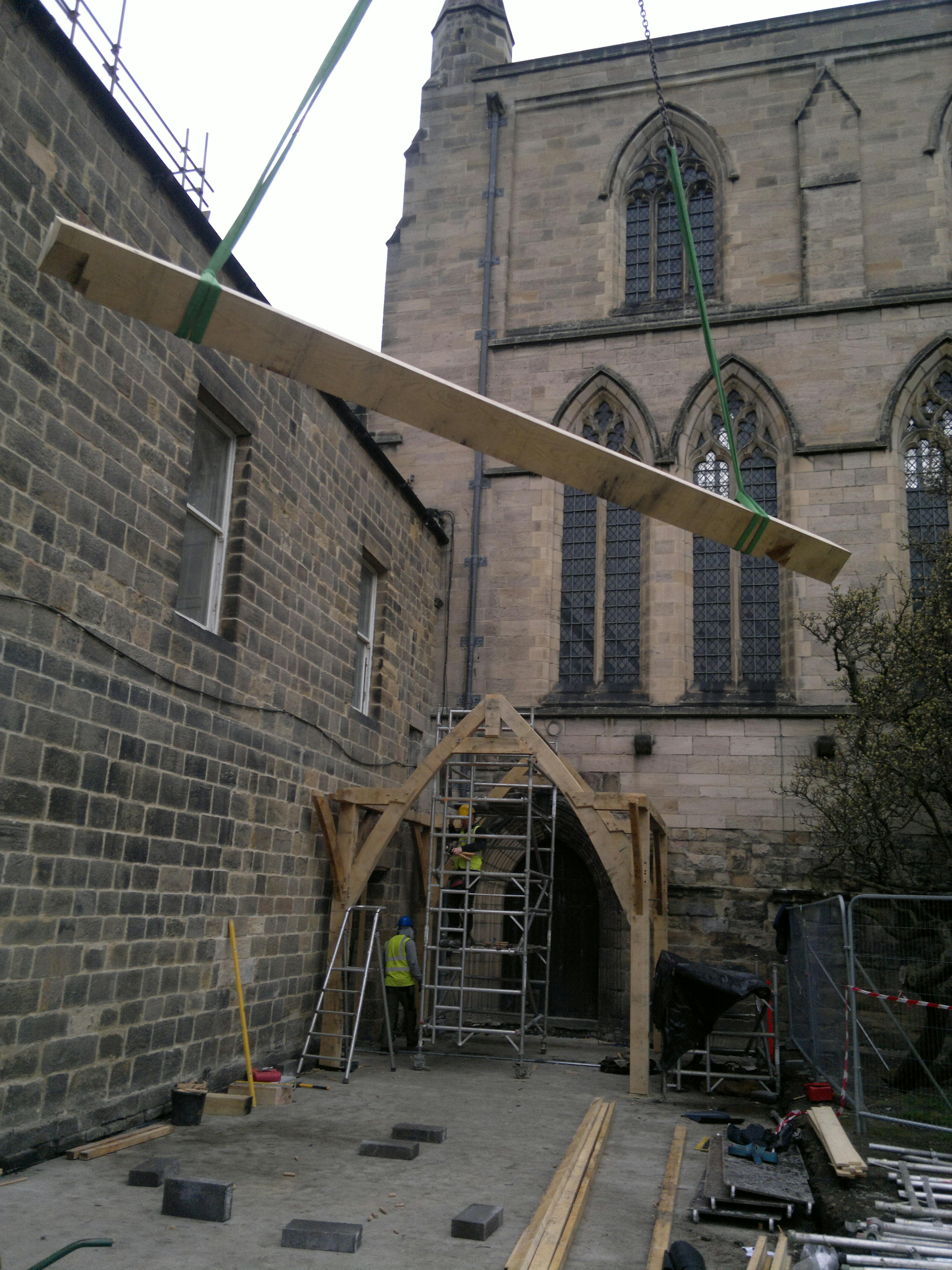 Beam being lifted into position for the oak-framed cloister