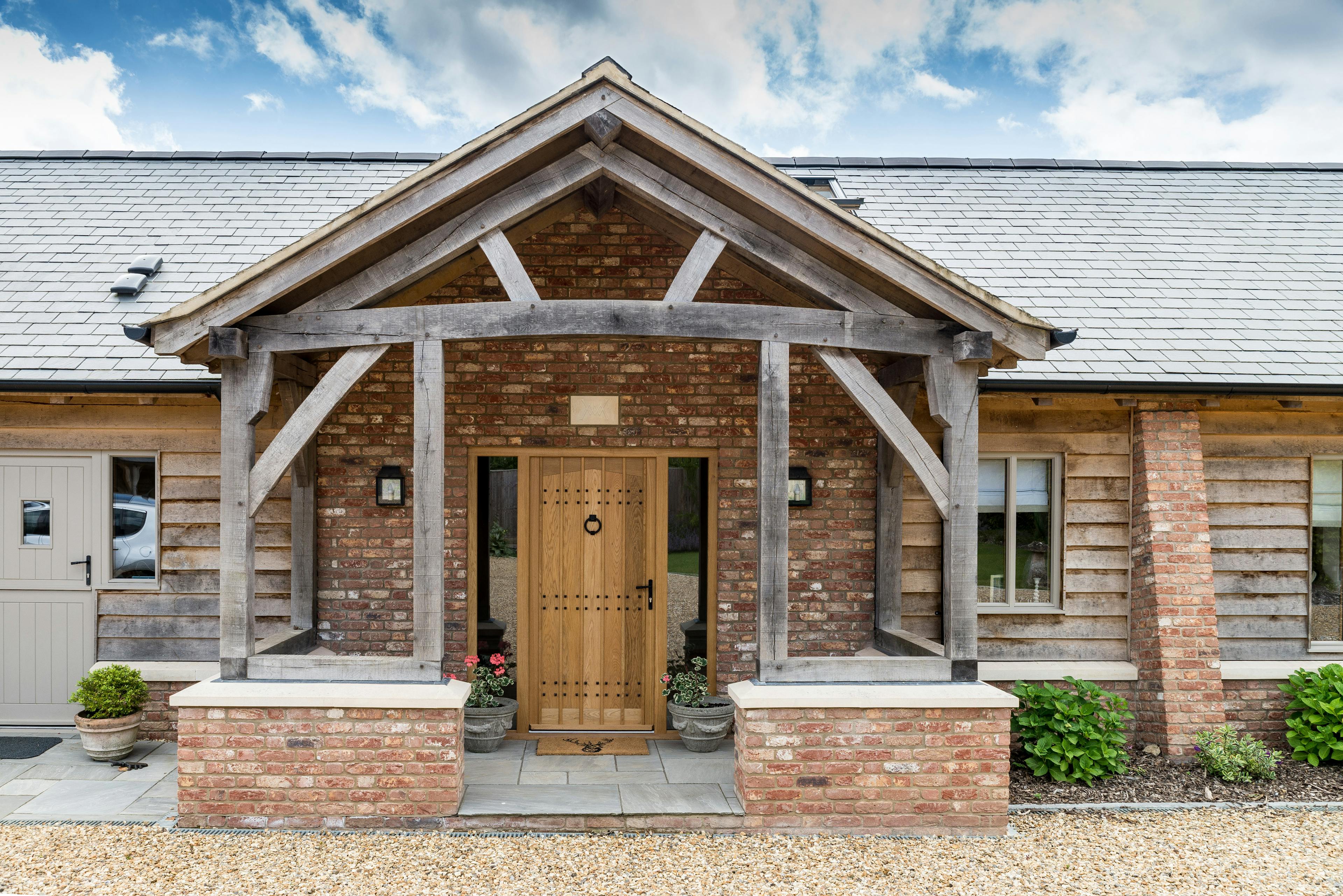 Oak-framed porch on a green oak barn-style home, combining classic design with modern charm