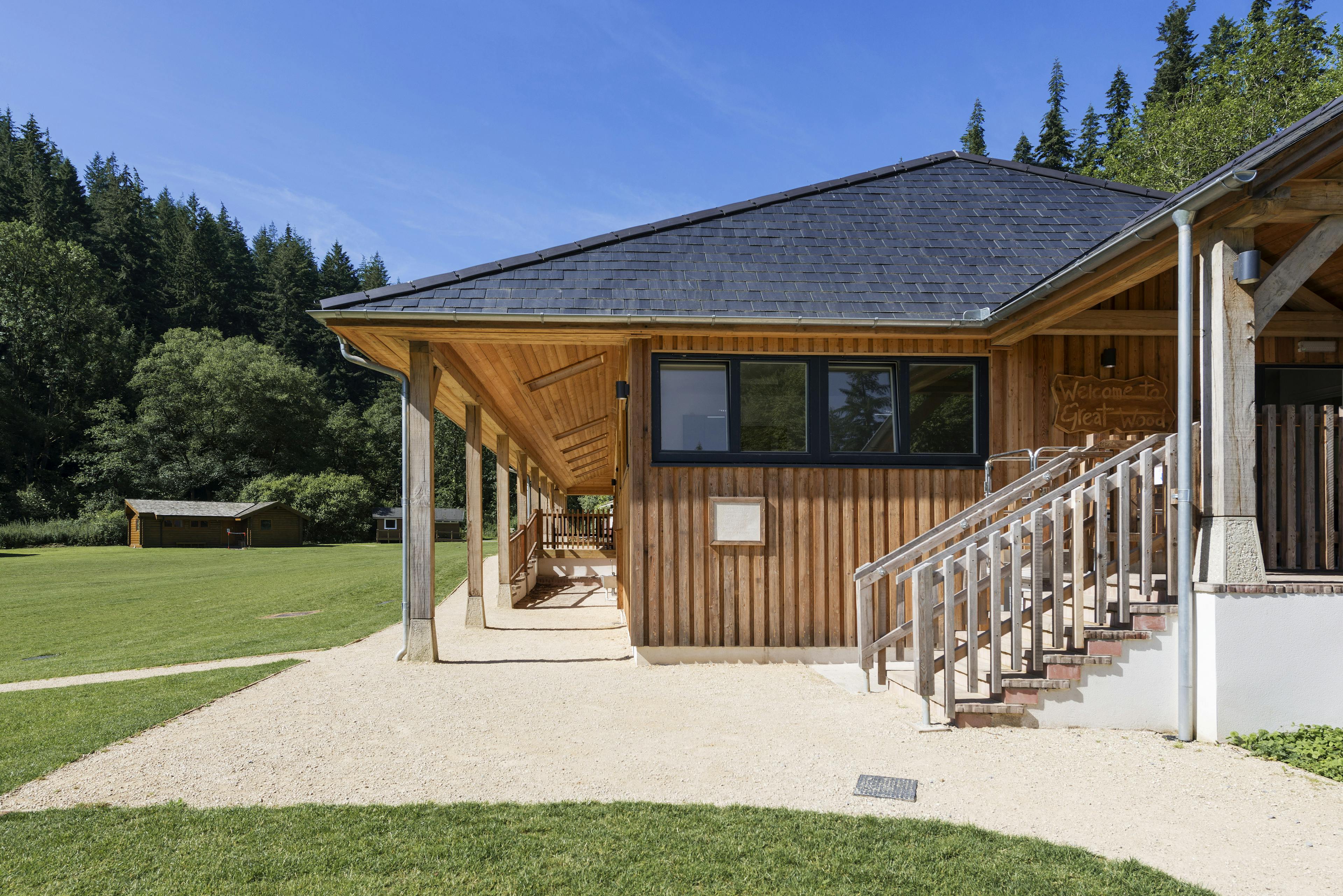 External view of the new multifunctional space at Great Wood Camp, surrounded by woodland