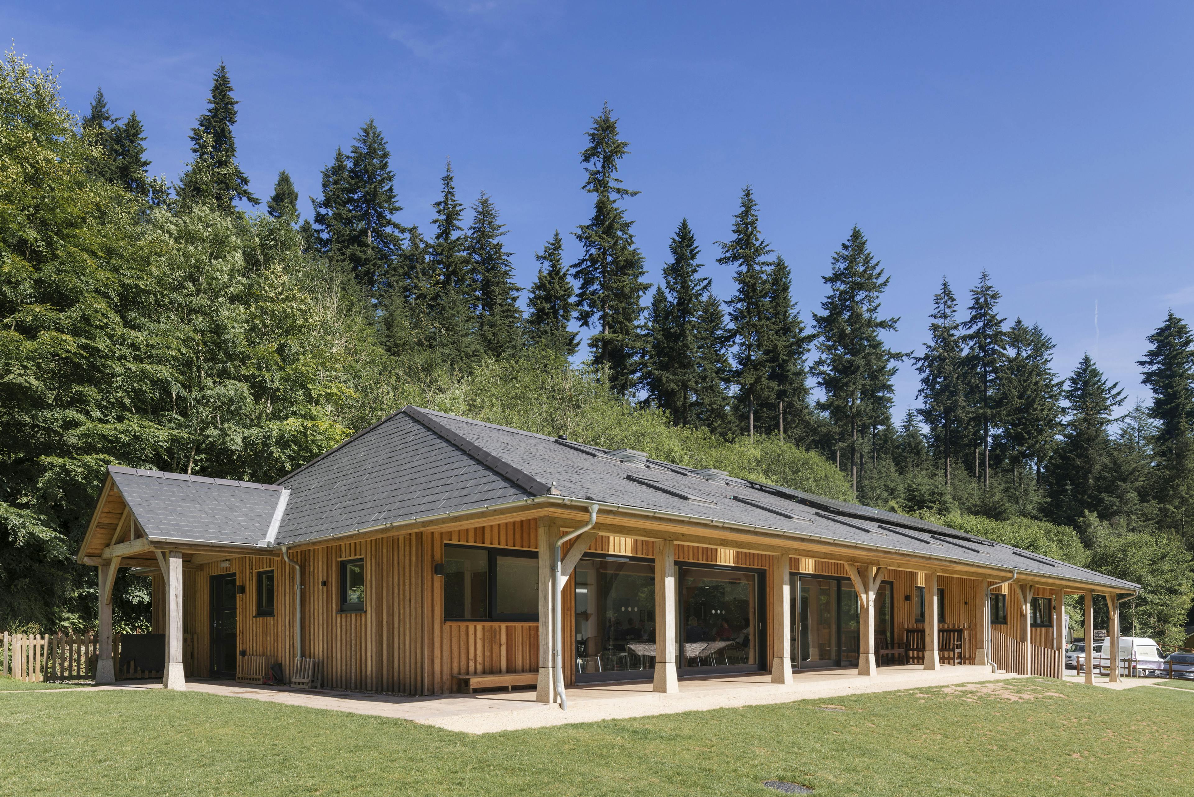 External view of the new multifunctional space at Great Wood Camp featuring a wraparound veranda