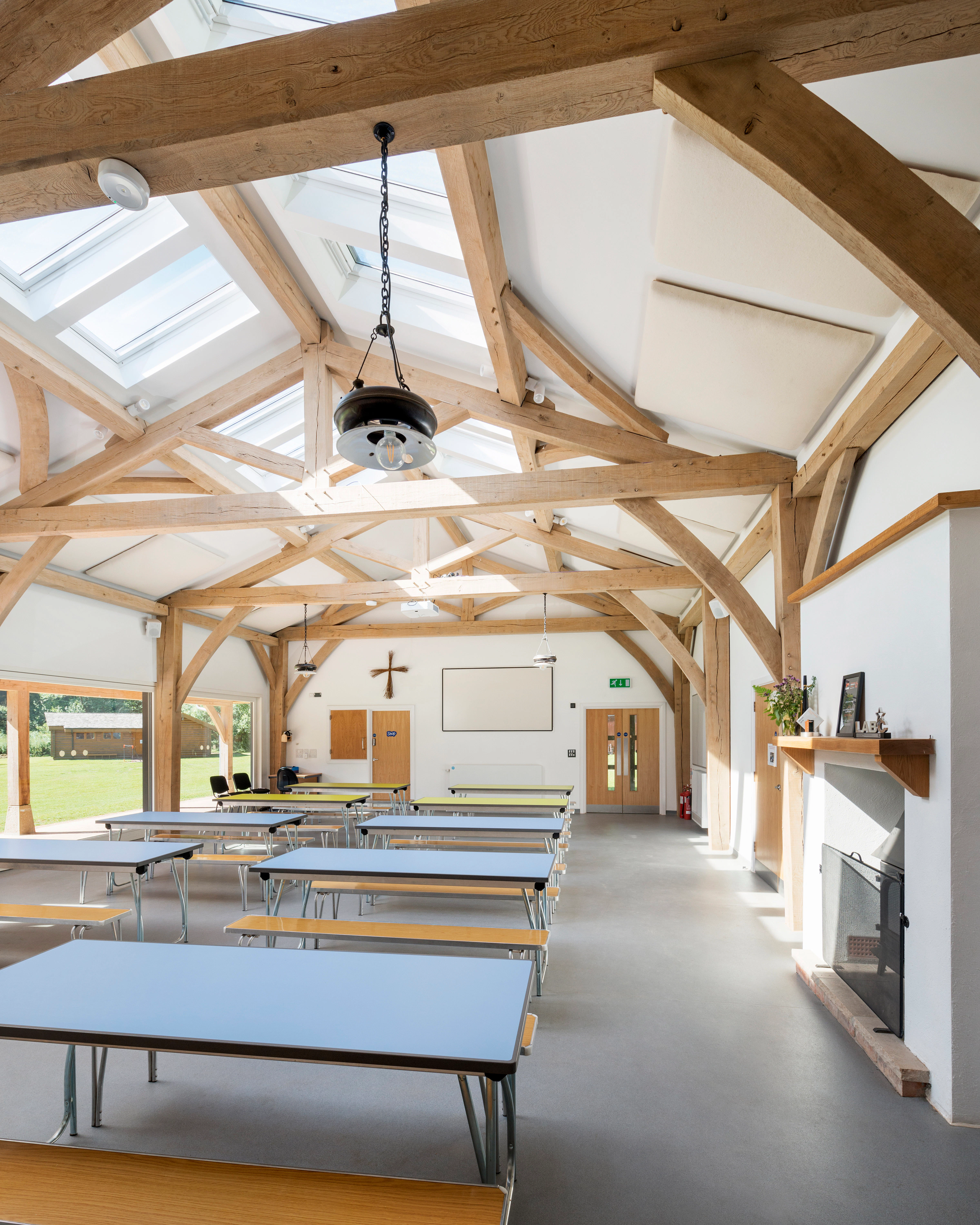 Interior view of the 4-bay multifunctional space at Great Wood Camp, showcasing exposed kingpost trusses