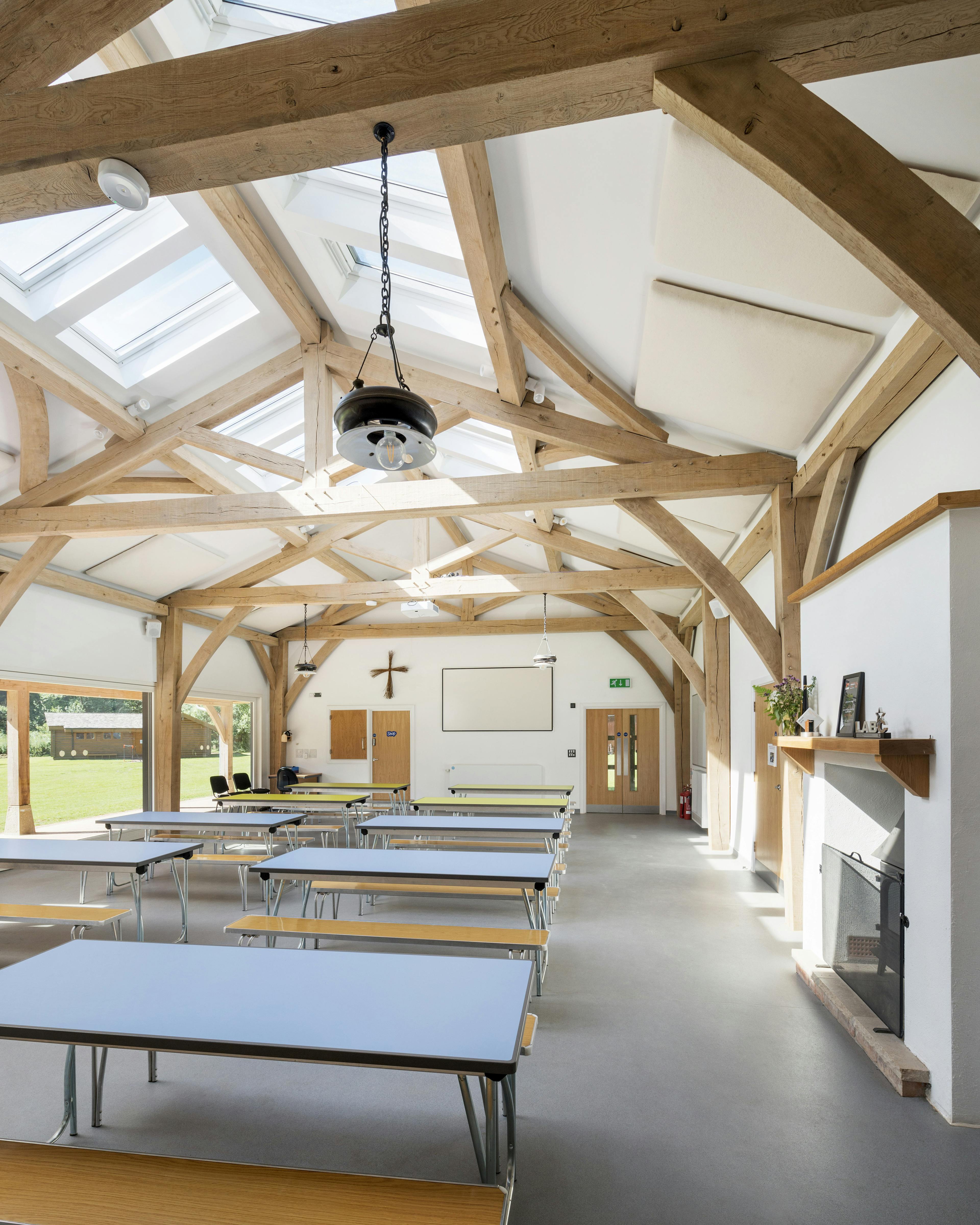 Interior view of the 4-bay multifunctional space at Great Wood Camp, showcasing exposed kingpost trusses