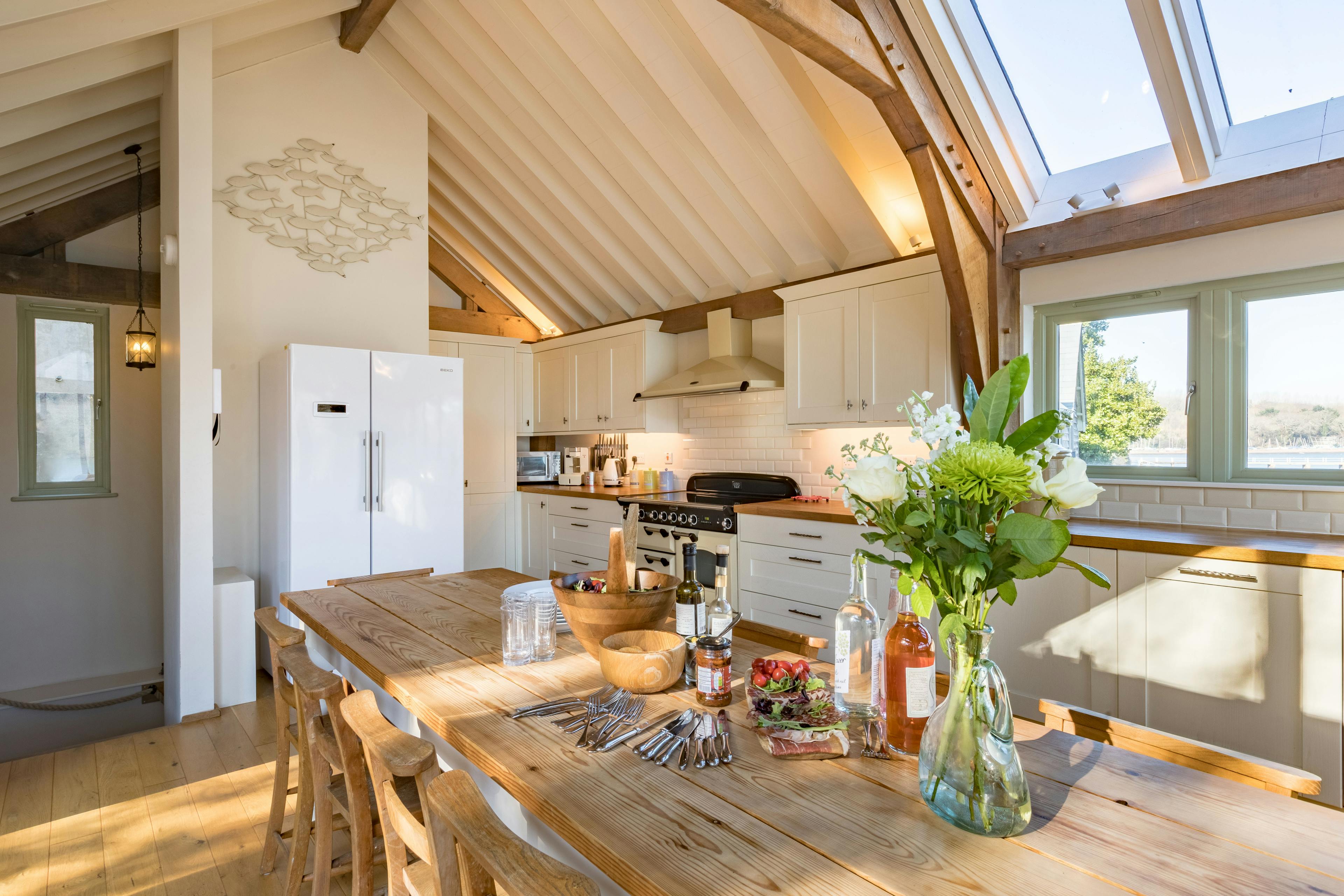 An internal view of an open-plan oak-framed cottage featuring a farmhouse-style kitchen