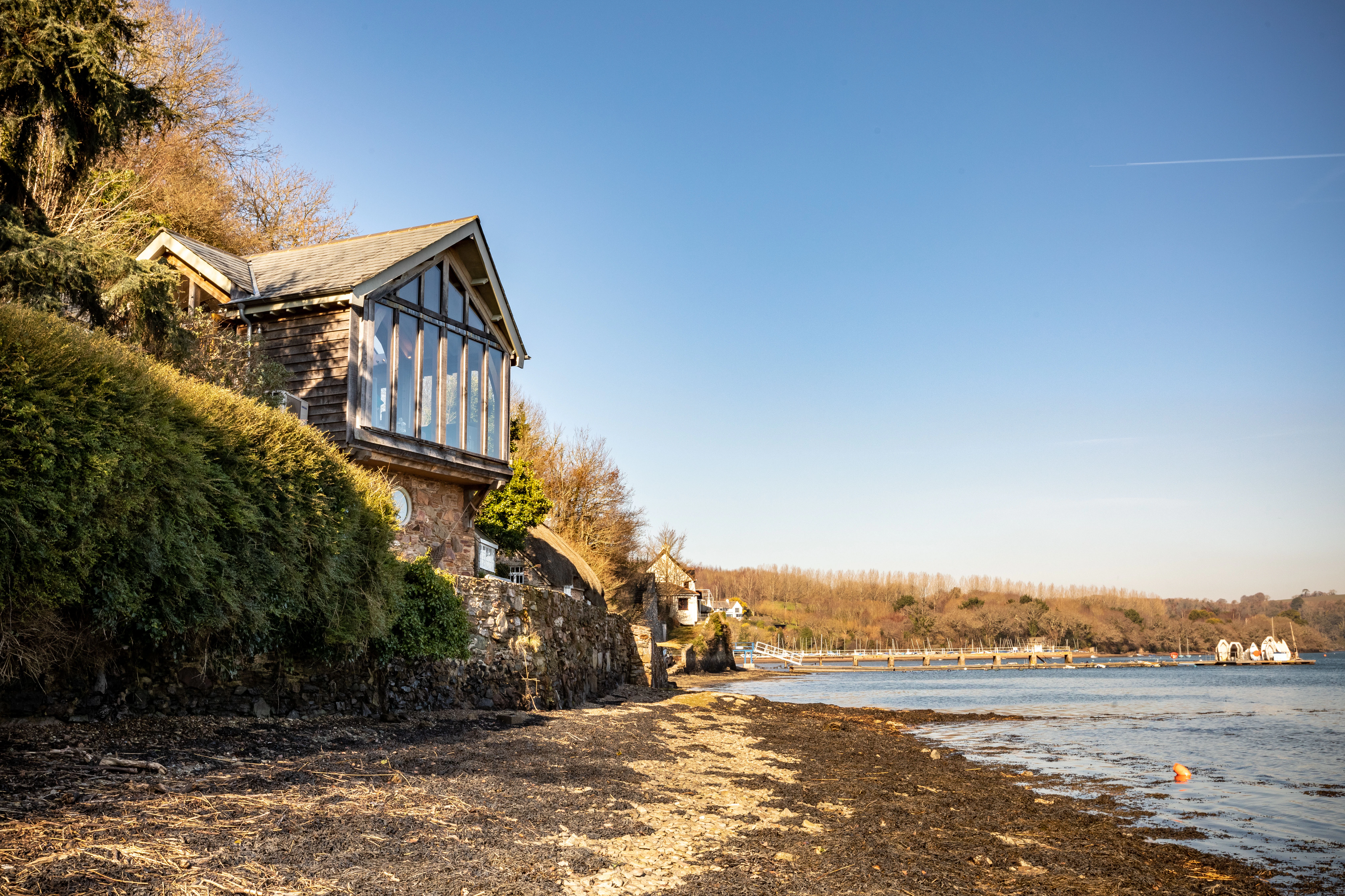 An oak-framed cottage situated on the edge of an estuary, featuring a glazed gable end to maximize the views