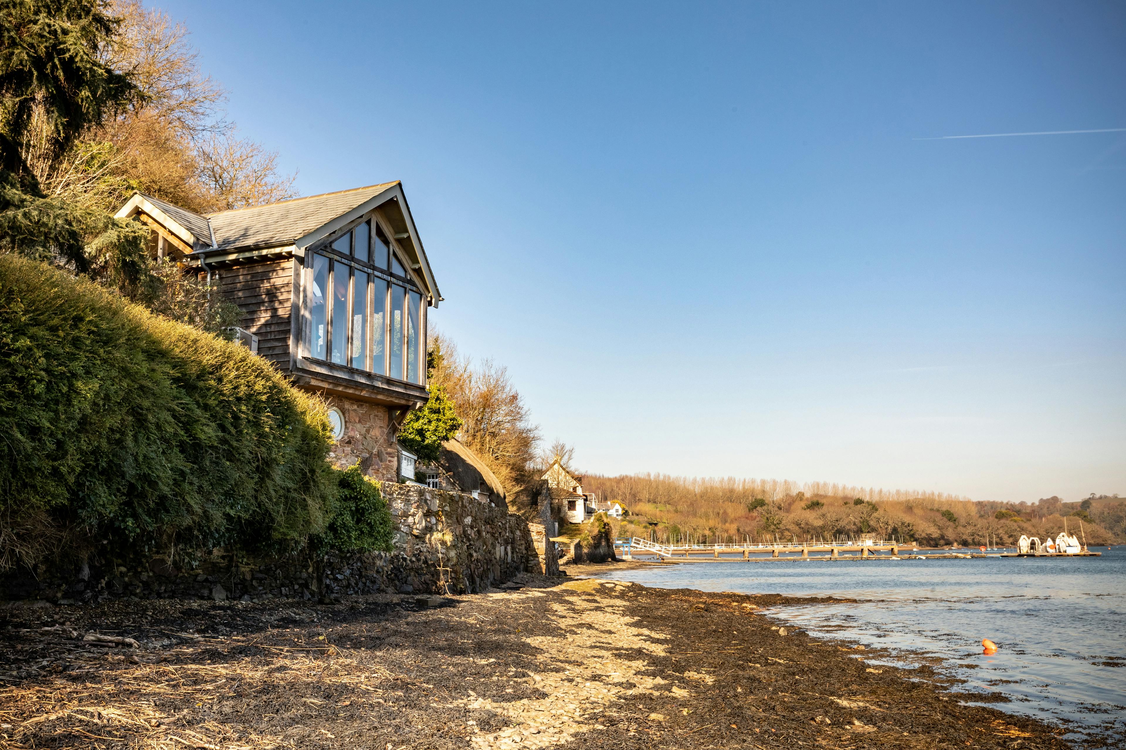 An oak-framed cottage situated on the edge of an estuary, featuring a glazed gable end to maximize the views