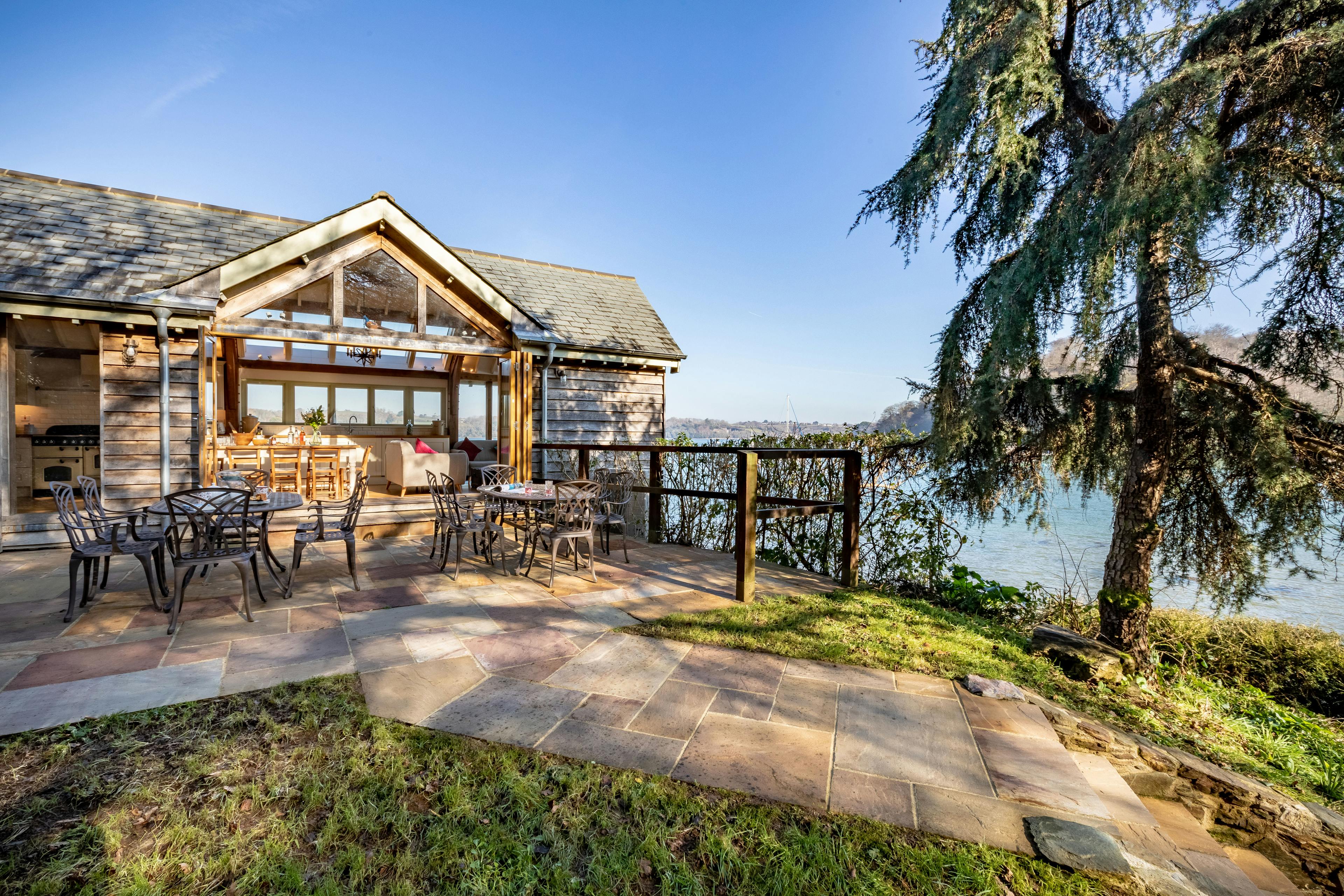 An oak-framed cottage with an elegant patio garden, offering stunning views of the estuary