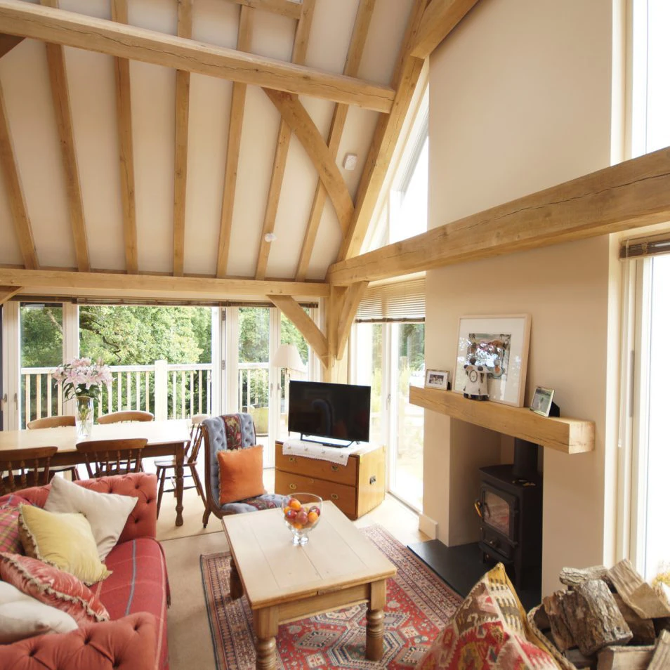 Oak-framed living space with vaulted ceilings and a central fireplace, creating a warm and cosy atmosphere
