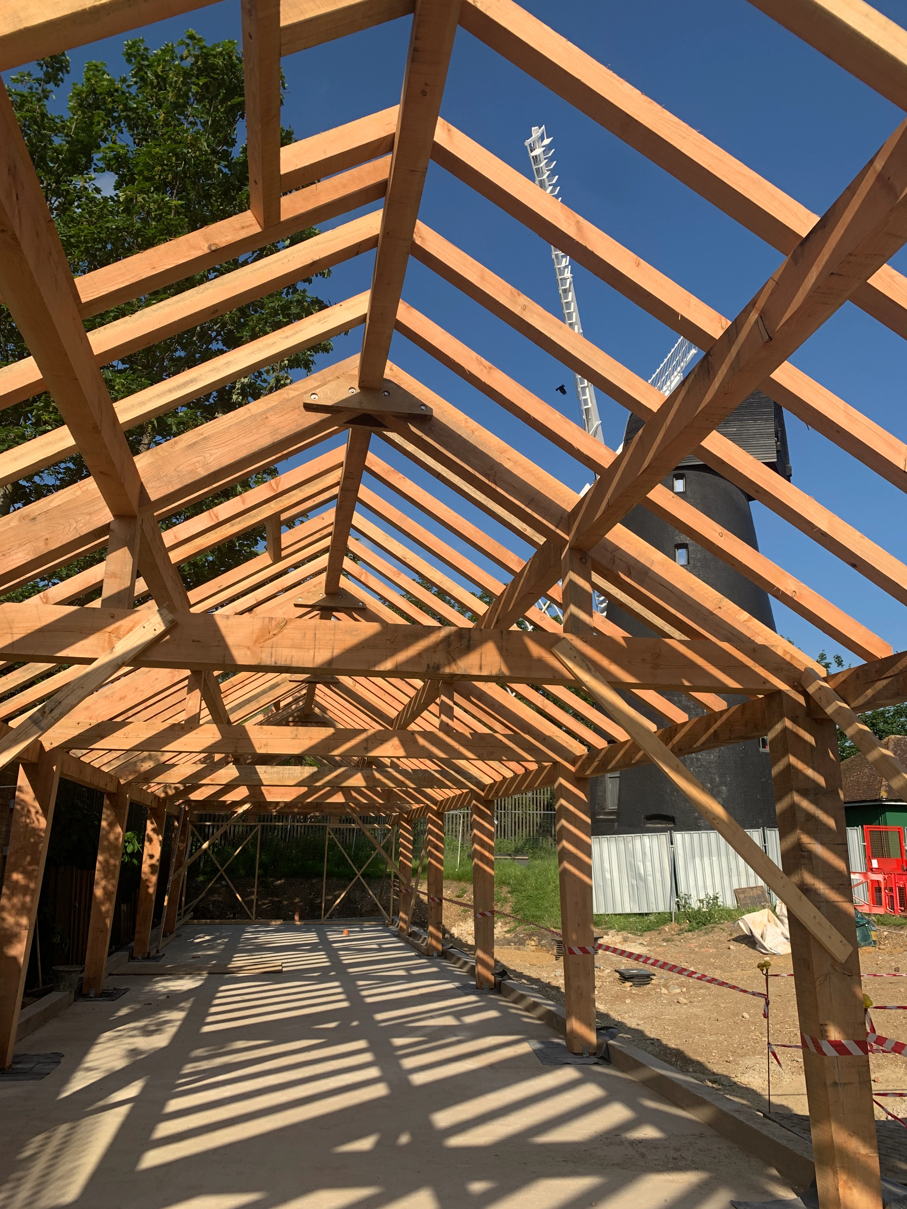 A Douglas fir framed community centre during construction with a blue sky behind