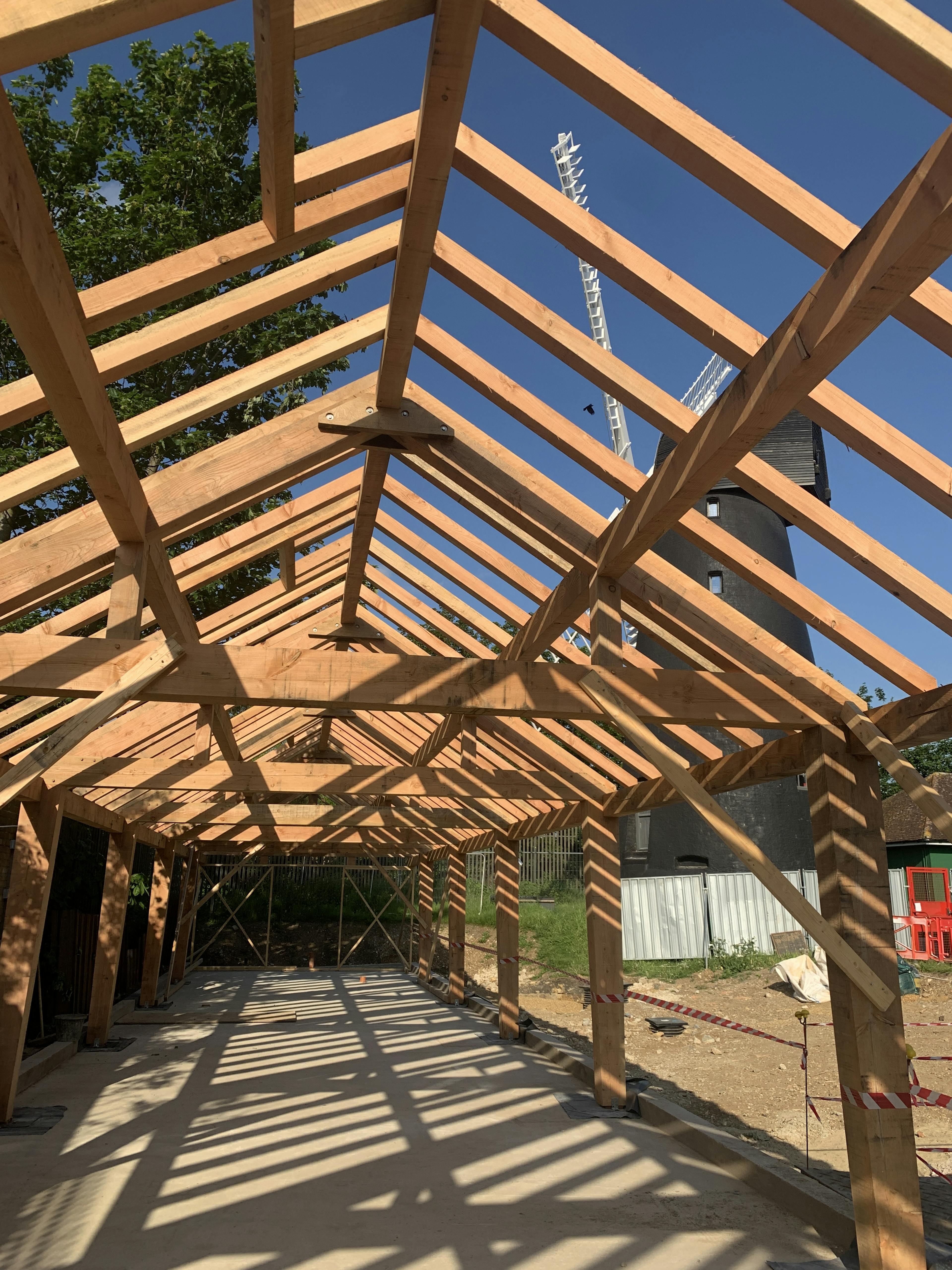 A Douglas fir framed community centre during construction with a blue sky behind