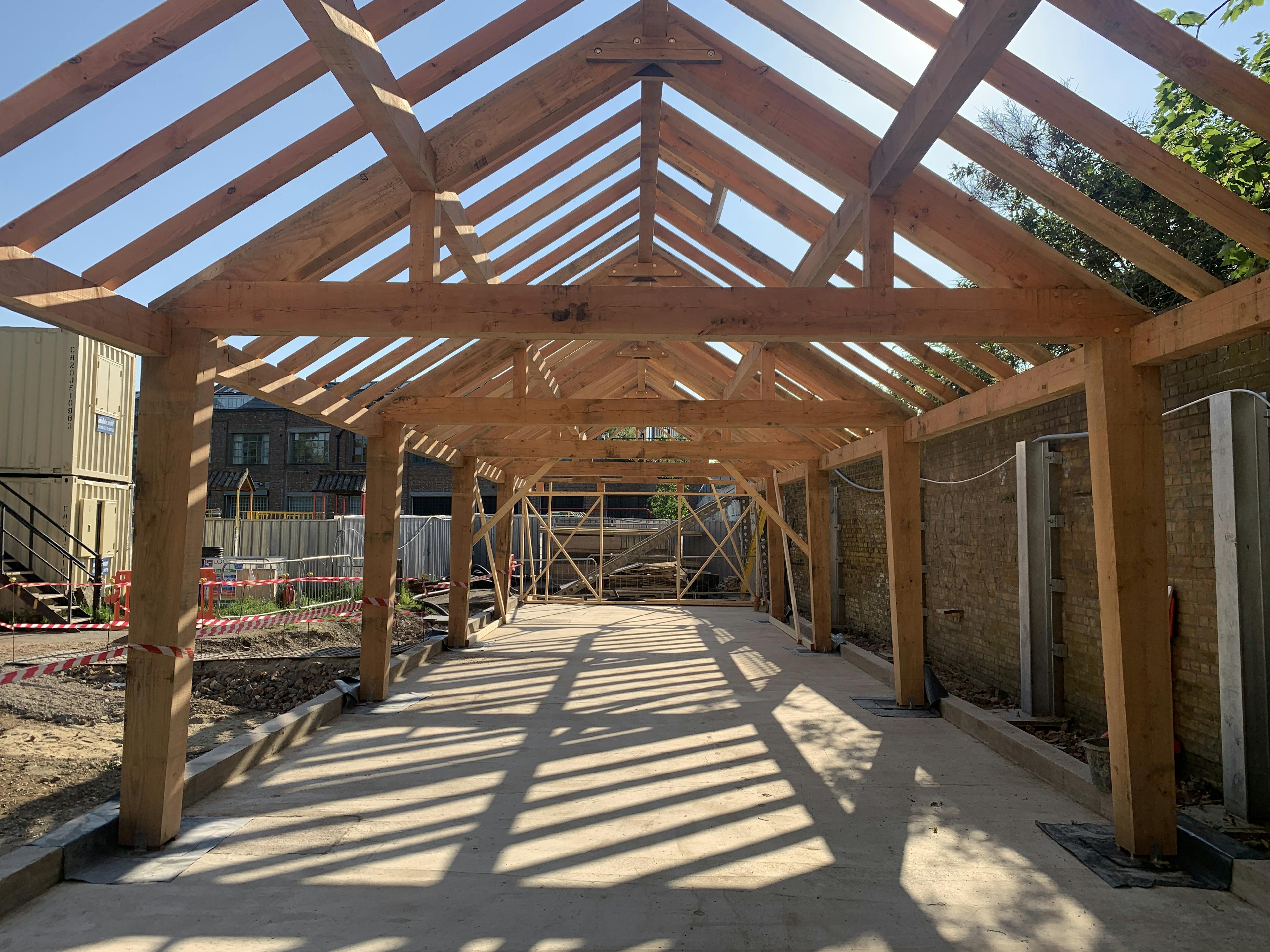 A Douglas fir framed community centre during construction with a blue sky behind