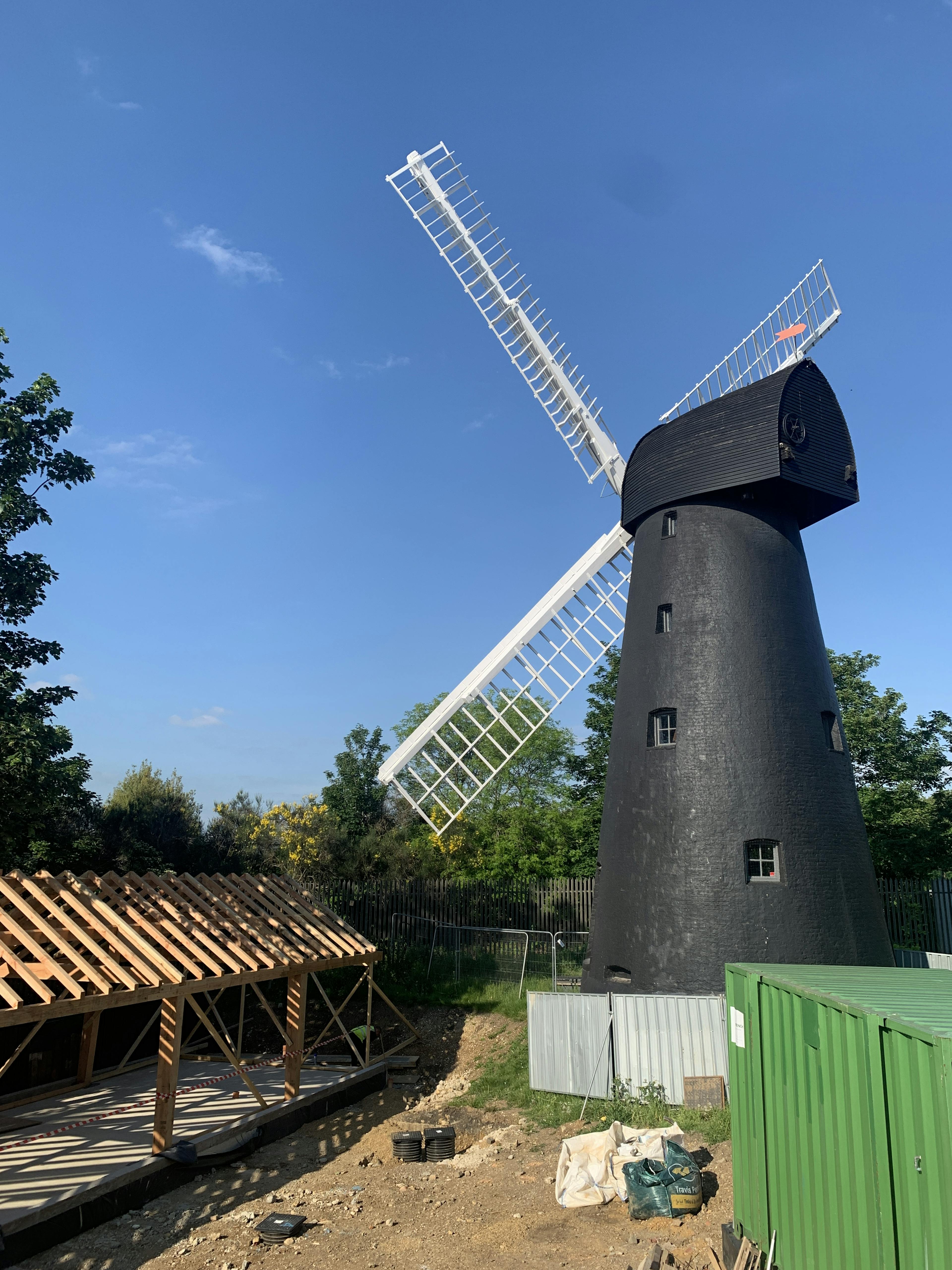 A Douglas fir framed community centre during construction next to a black clad windmill