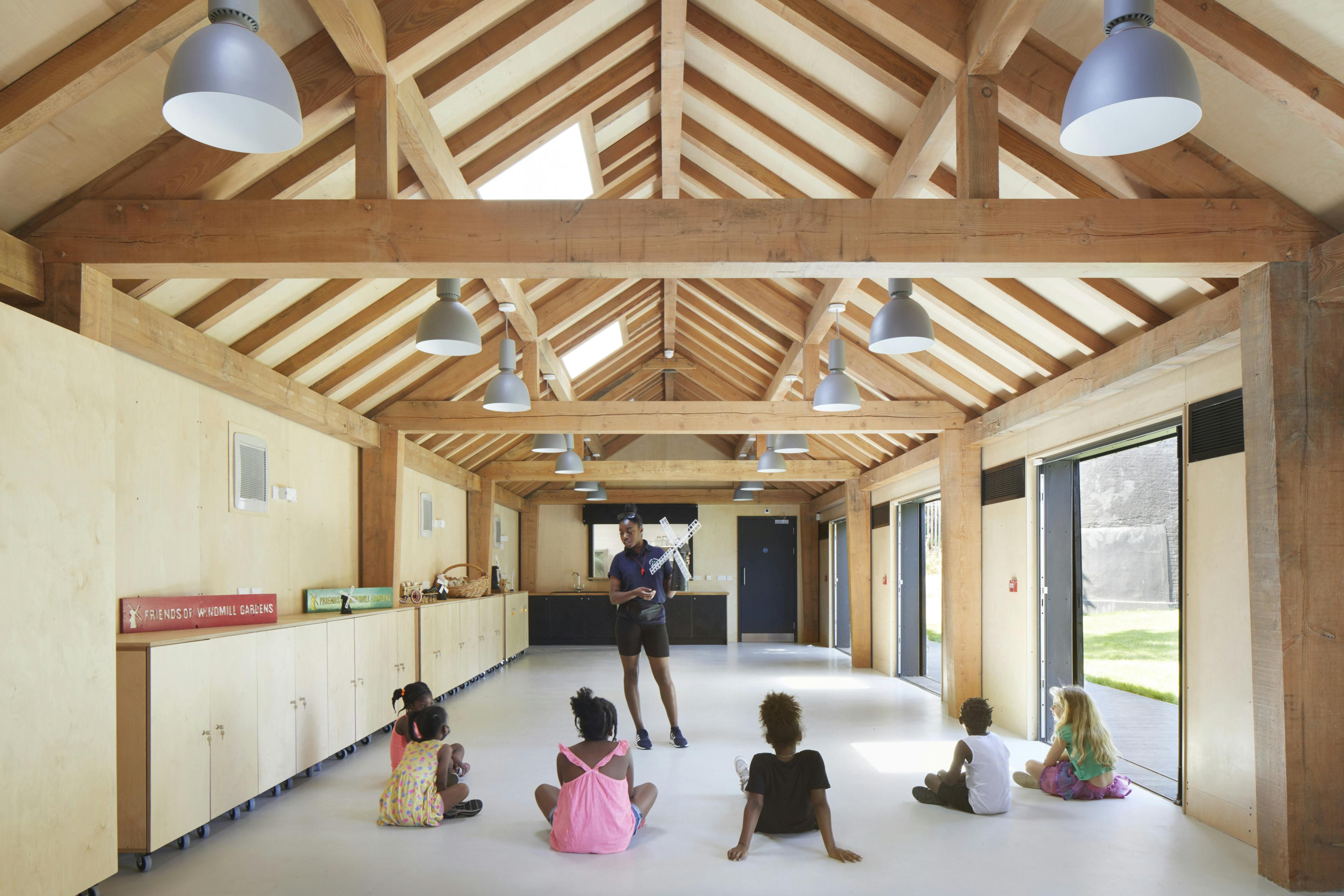 A teacher and children in a Douglas fir framed community centre