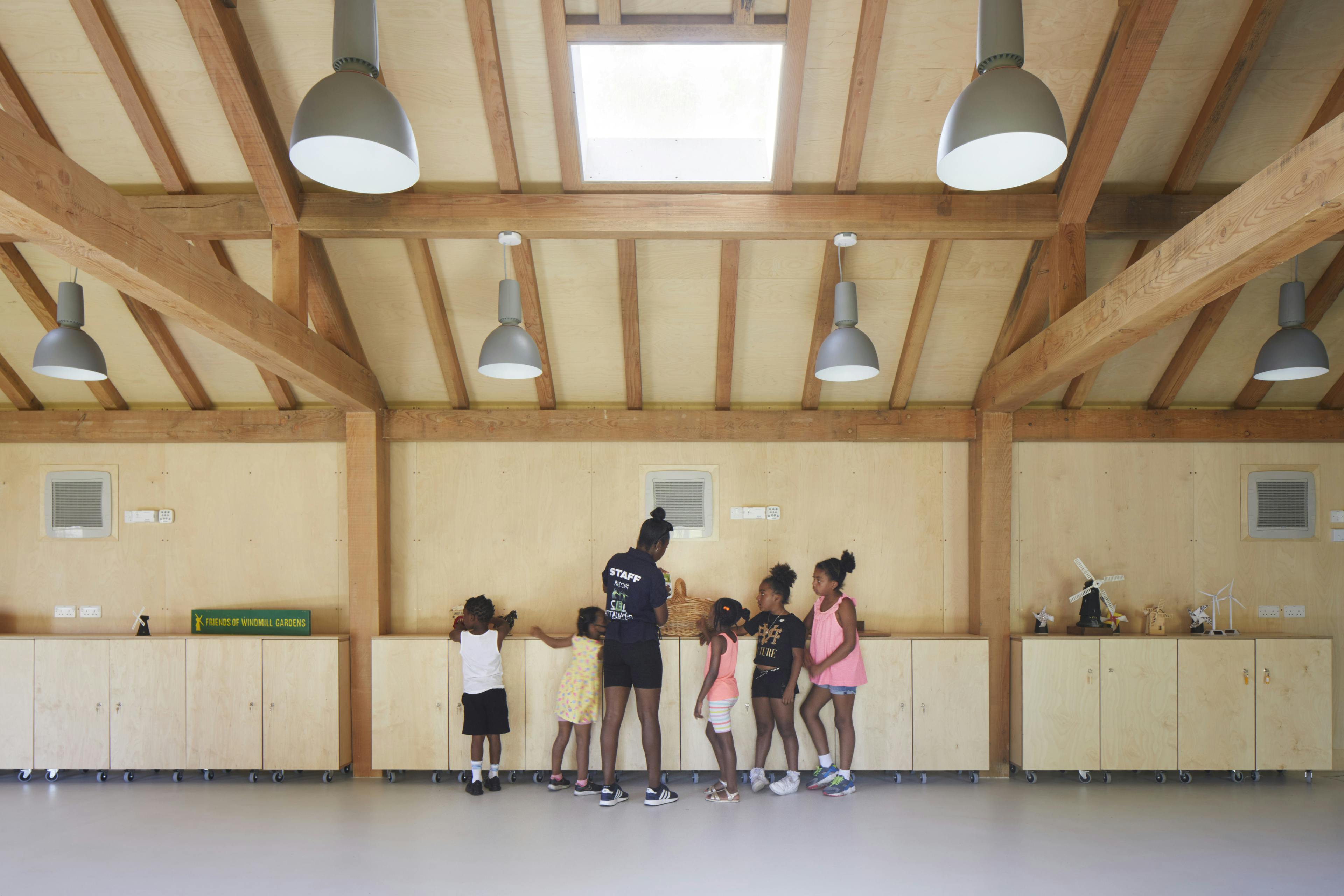A teacher and children in a Douglas fir framed community centre