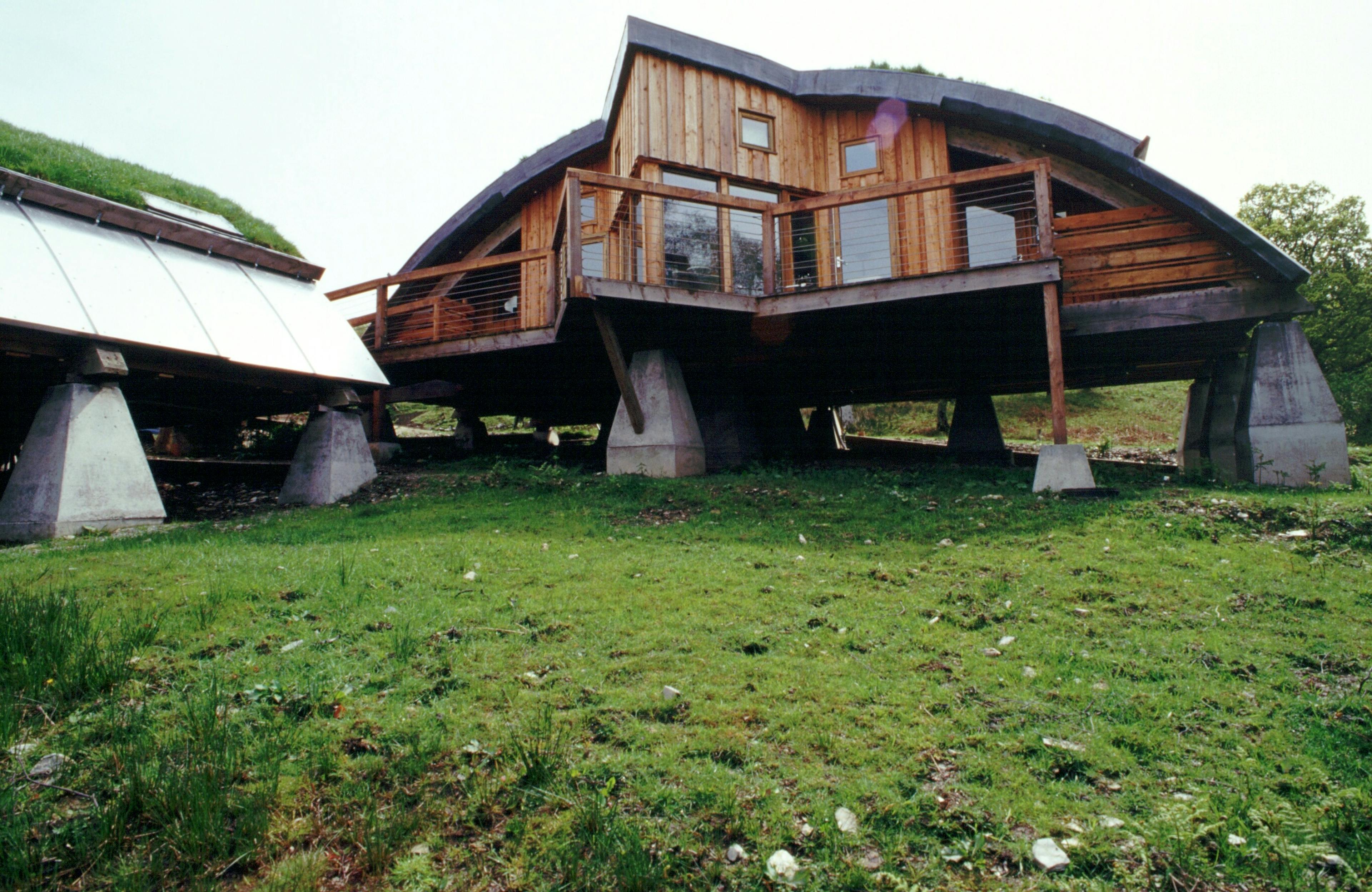 Green oak and Douglas fir clad cabins with a turfed curved roof and a balcony decking