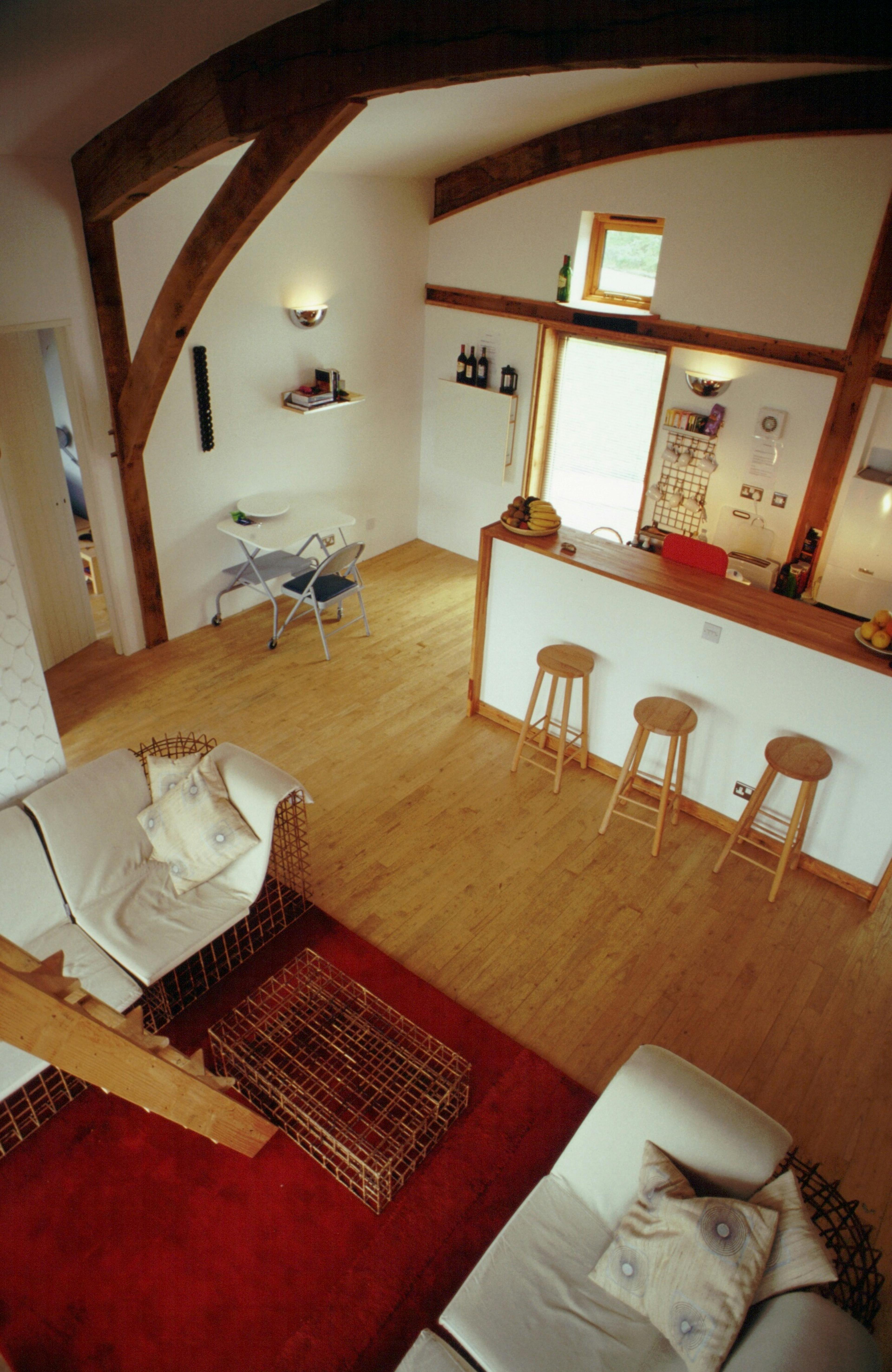 Interior of a green oak and Douglas fir clad cabin showing the kitchen and living area