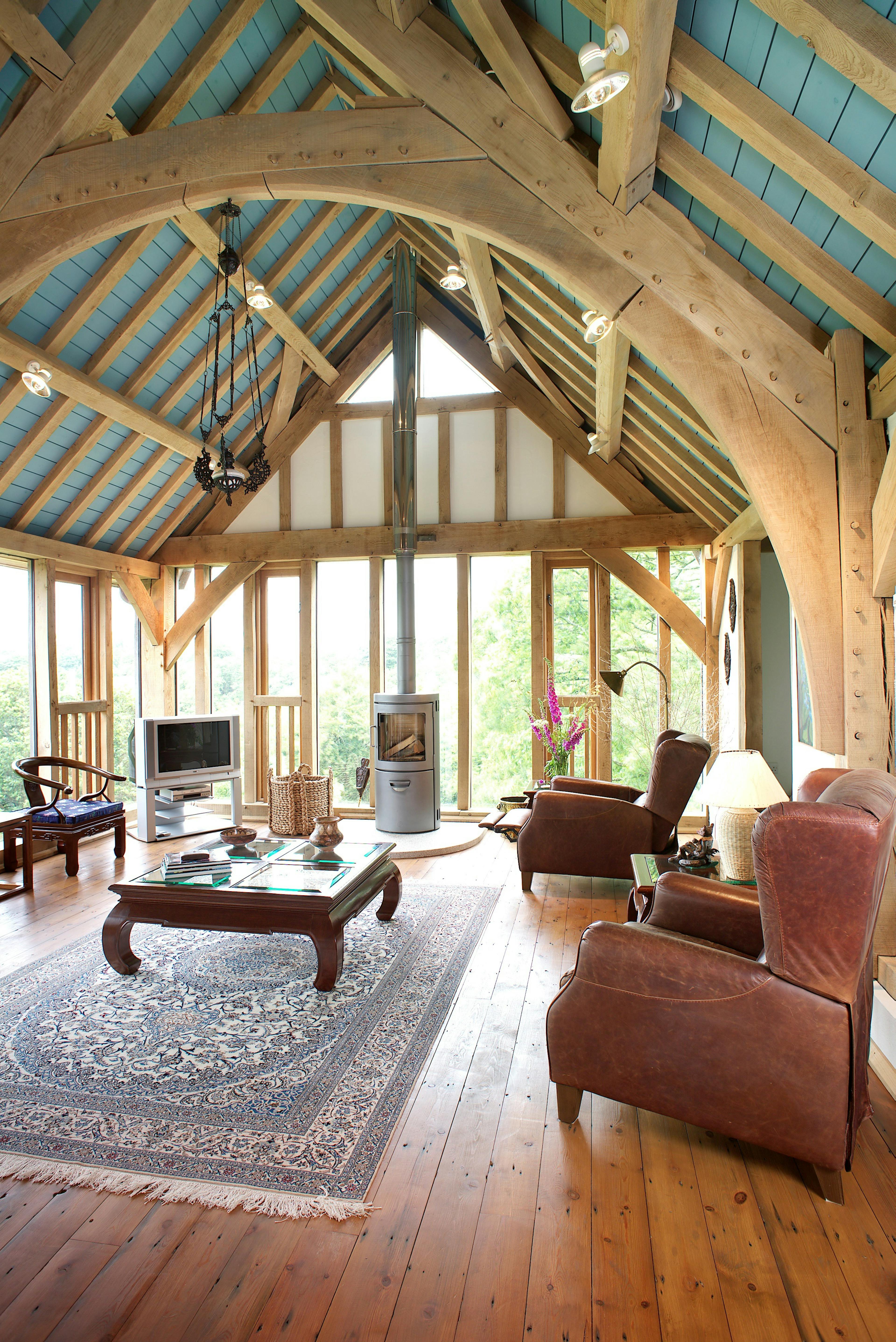 The large sitting room of an oak frame home with a large oak truss
