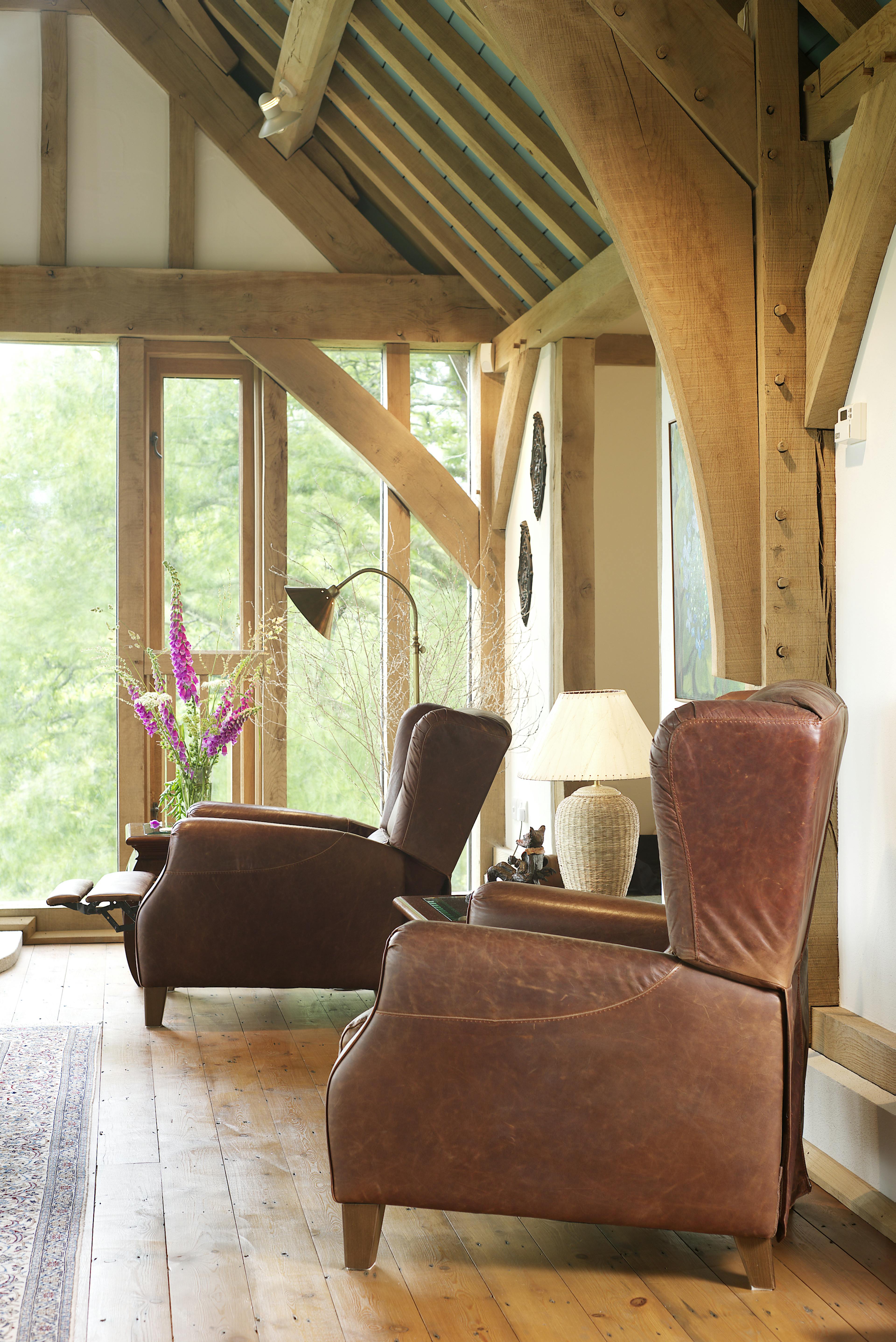 The sitting room of an oak frame home with two armchairs under the oak trusses