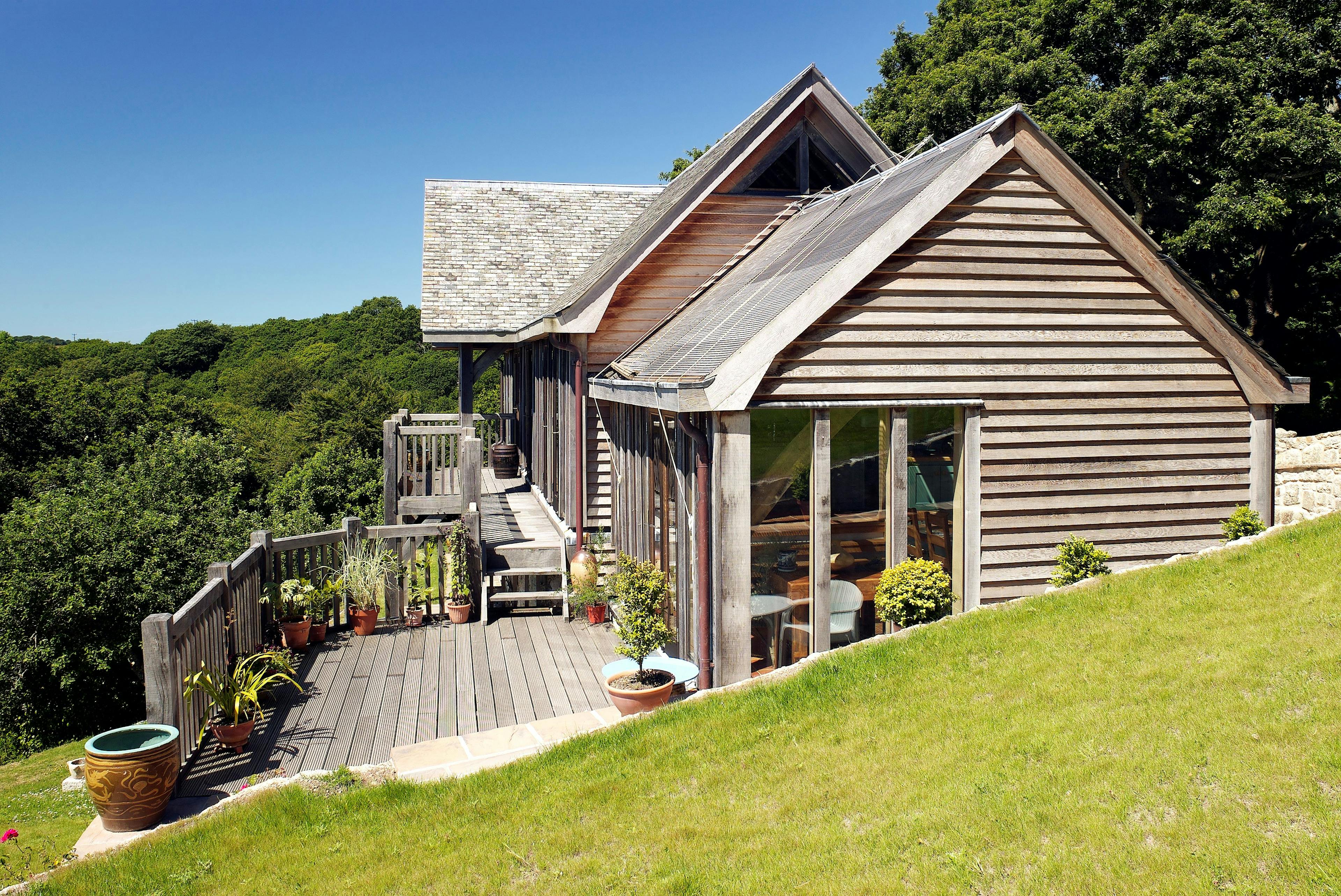 Oak frame home with oak balcony built on a slope with green lawn in front