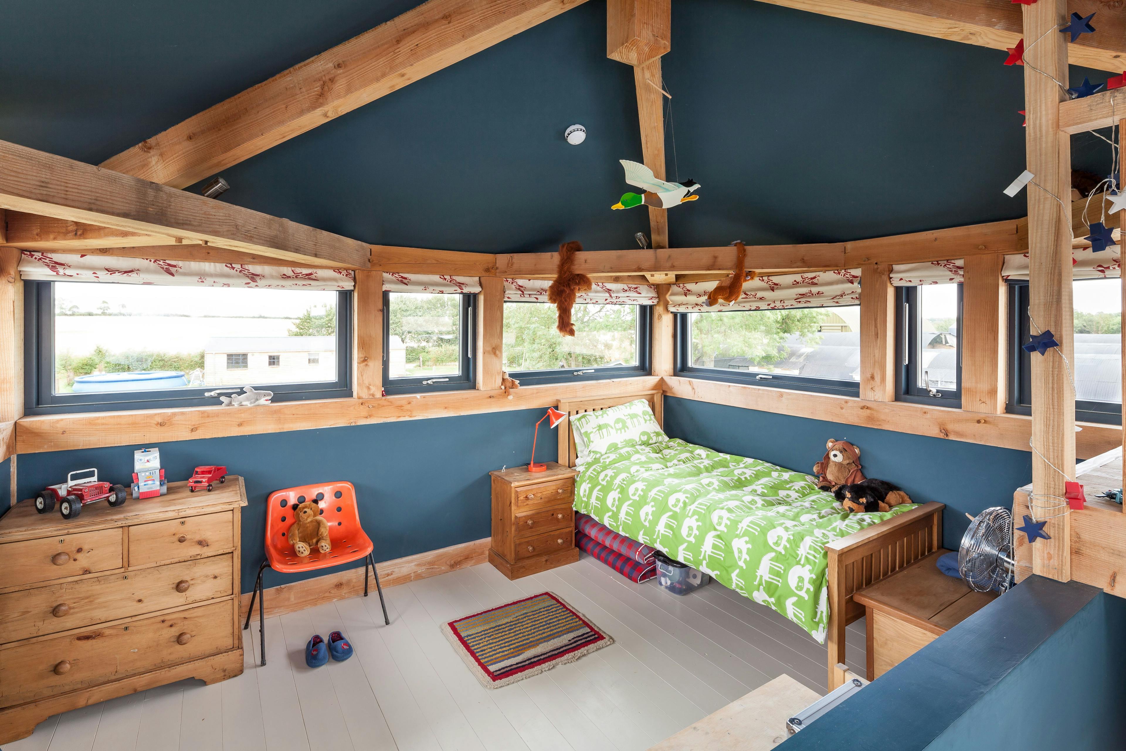 A bedroom in a Douglas fir framed family farmhouse with blue painted walls