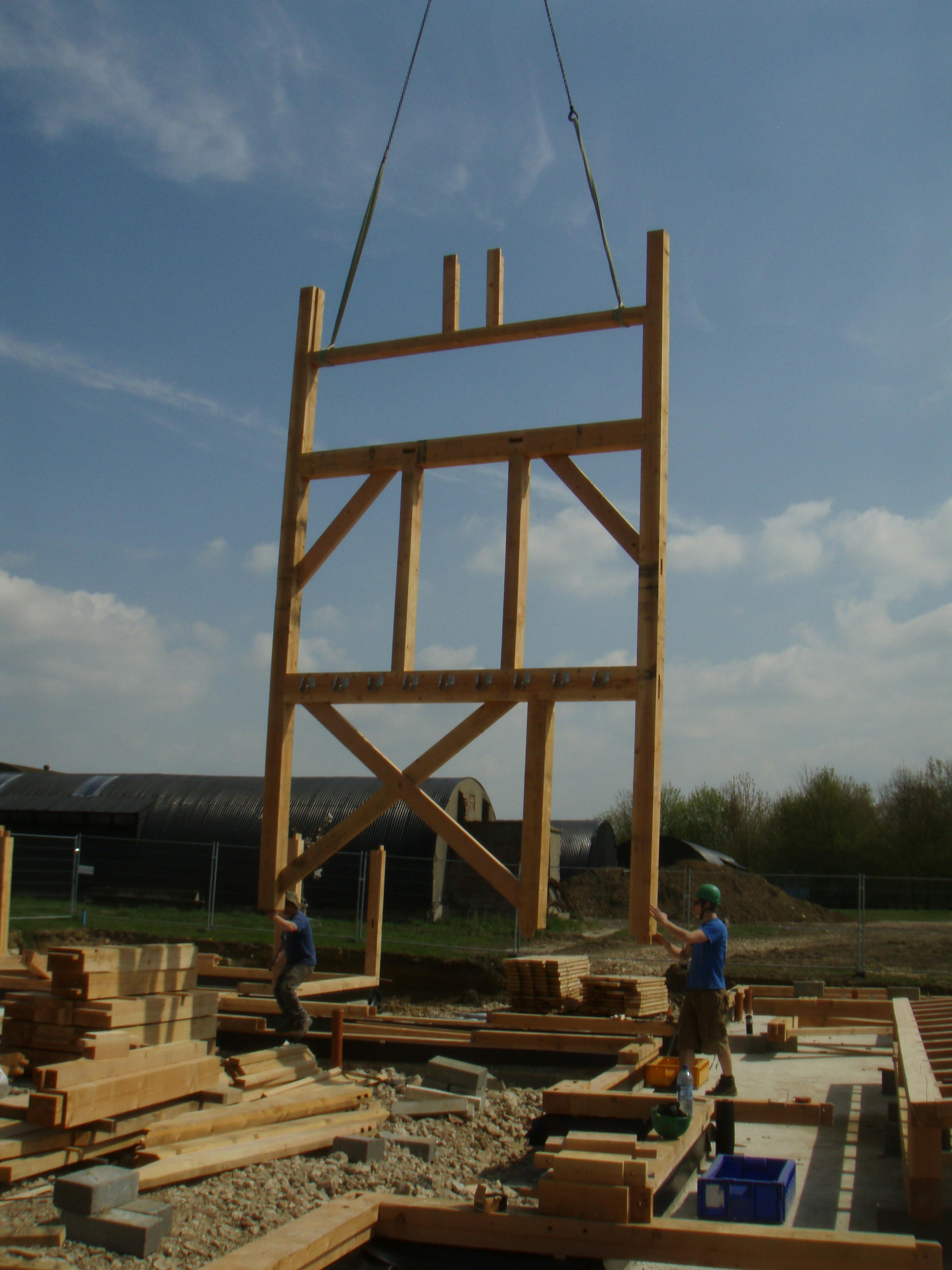 A crane lifts a section of a Douglas fir framed large family farmhouse during installation