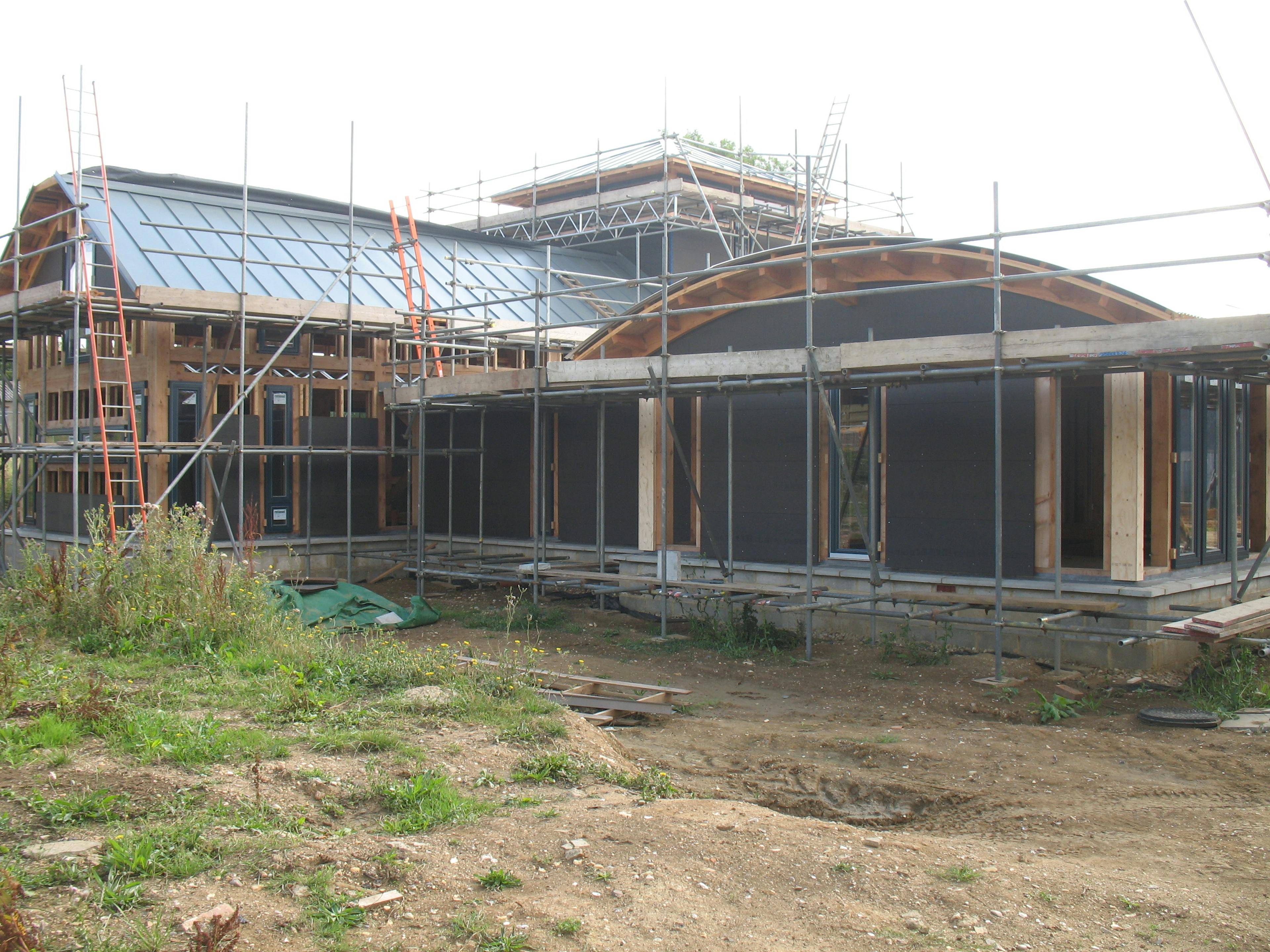 A Douglas fir framed large family farmhouse during installation with some of the wrapping of the frame showing