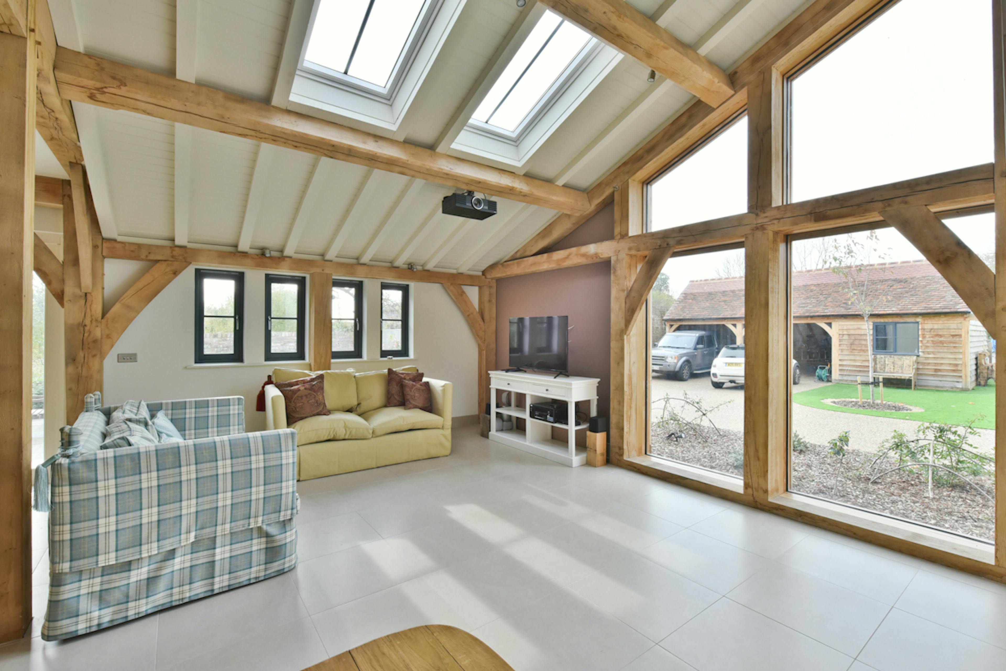 A sitting area in an oak framed extension to a 17th century pub with glazing and views of a garden
