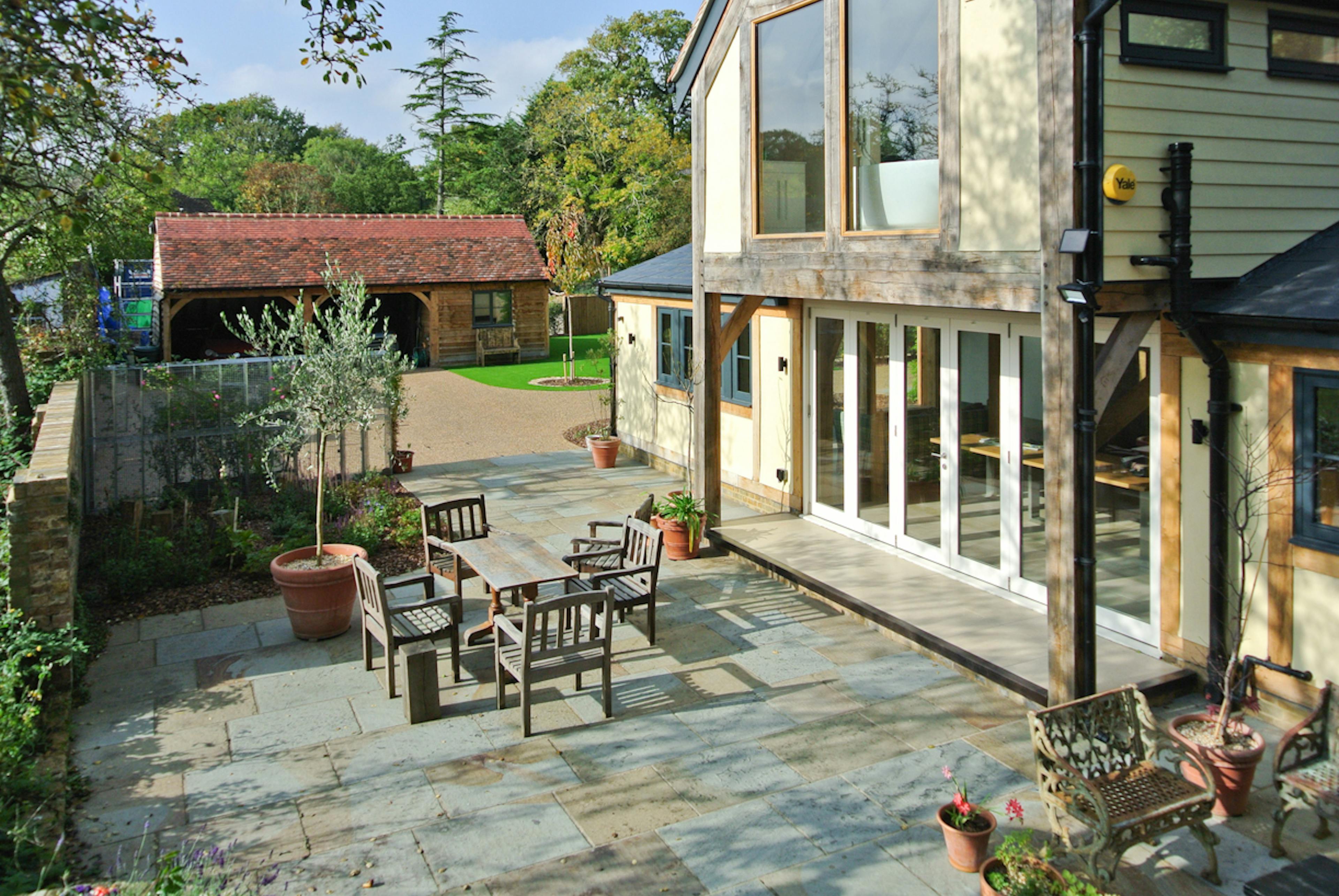 Exterior view of an oak framed extension to a 17th century pub with a courtyard and external table and chairs