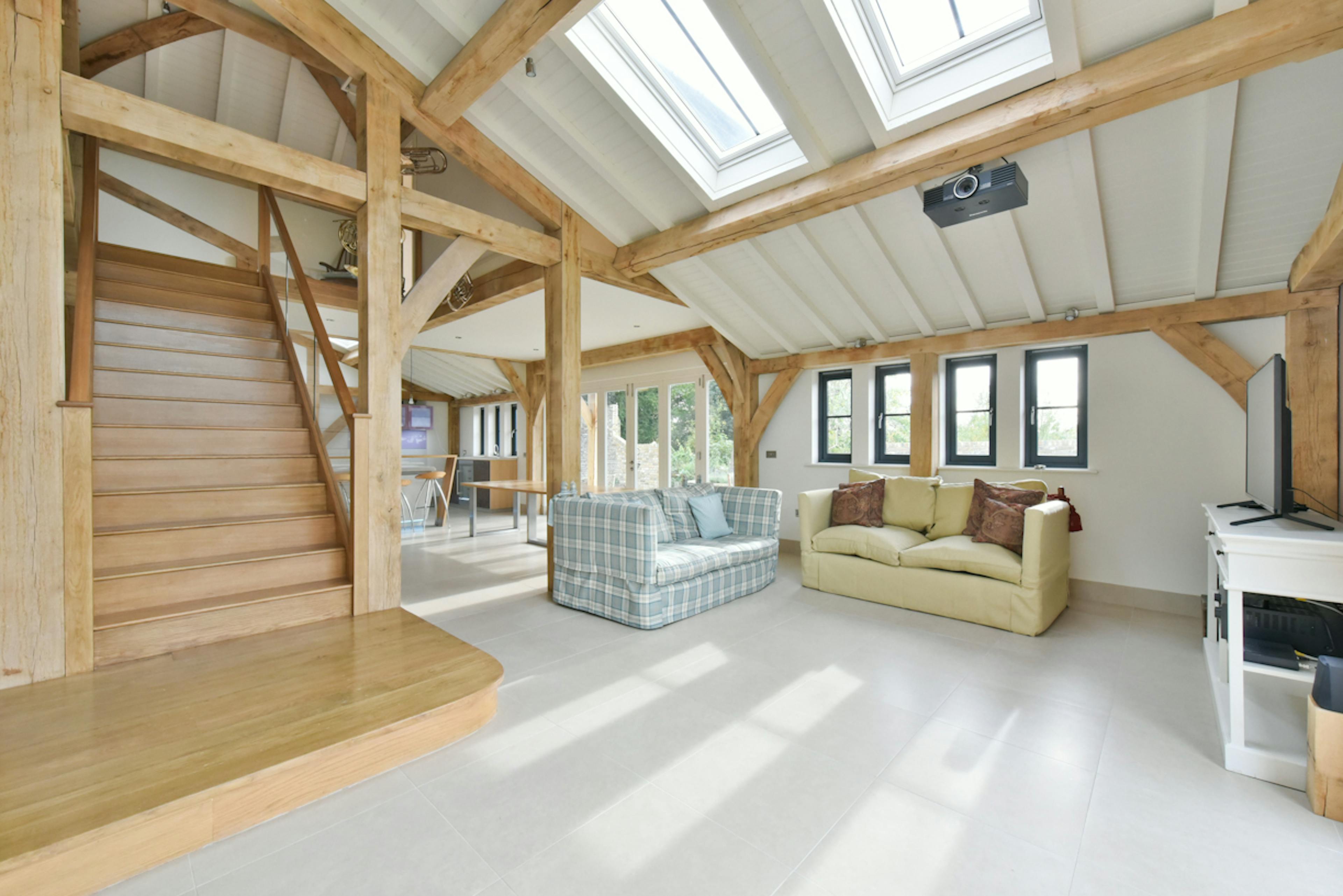 An open plan kitchen, dining and sitting area with a wooden straicase in an oak framed extension to a 17th century pub