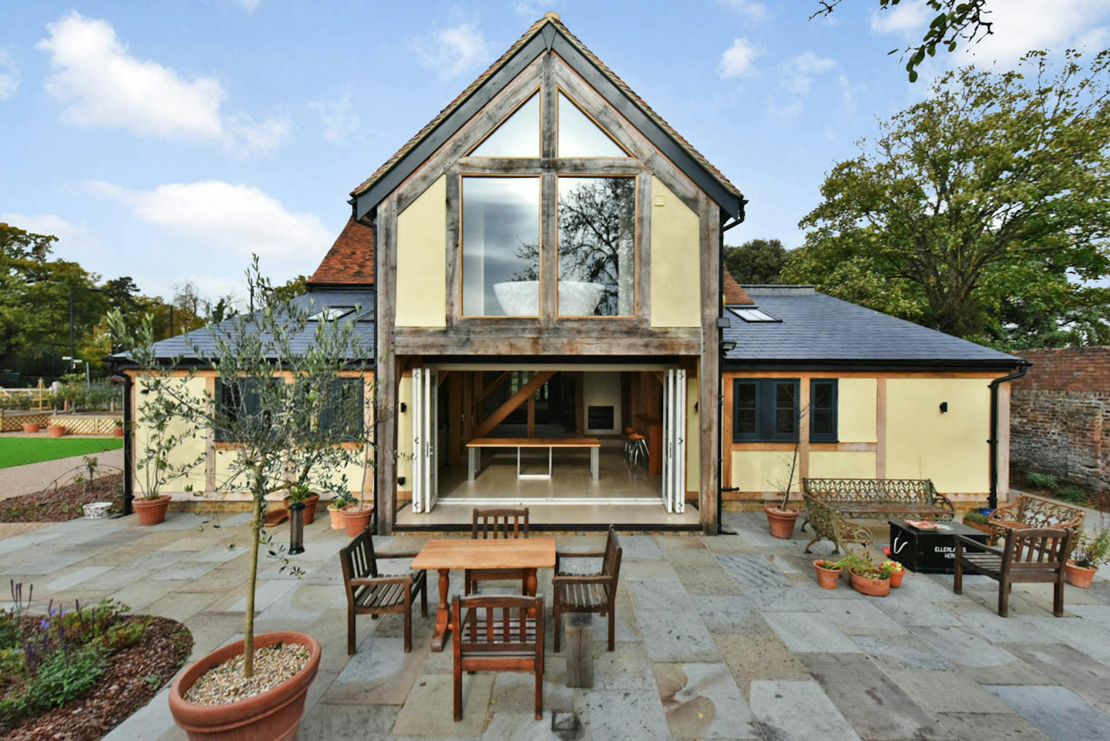 Exterior view of an oak framed extension to a 17th century pub with a courtyard and external table and chairs