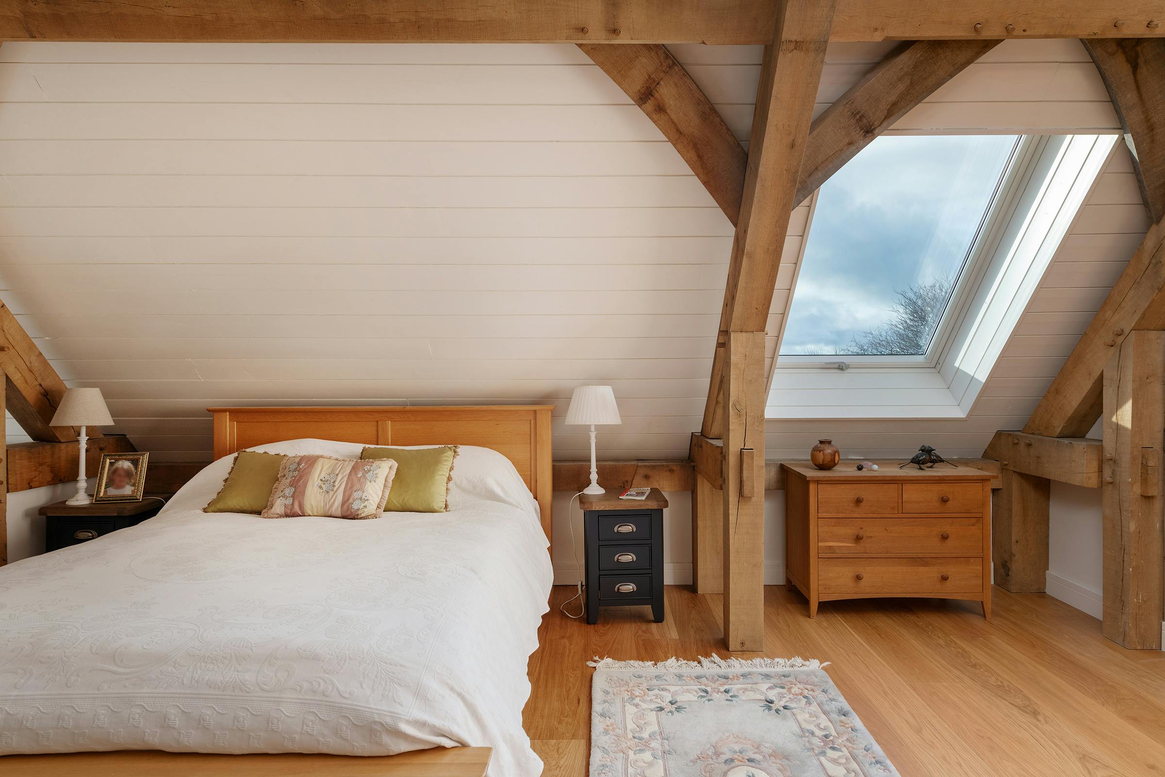 A mezzanine bedroom with a velux window in an oak frame home