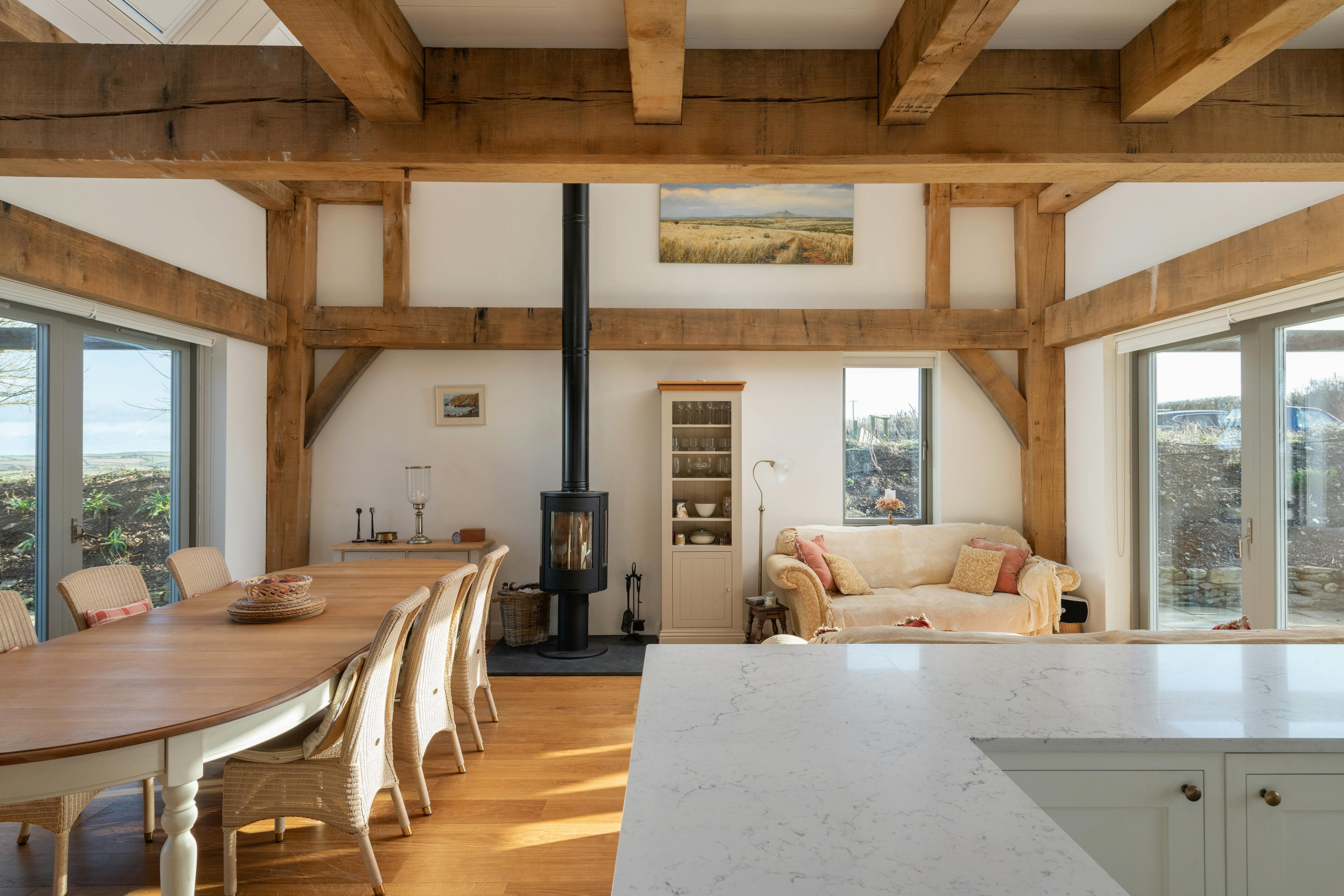 An open plan kitchen, dining and sitting area with a log burner in an oak framed home