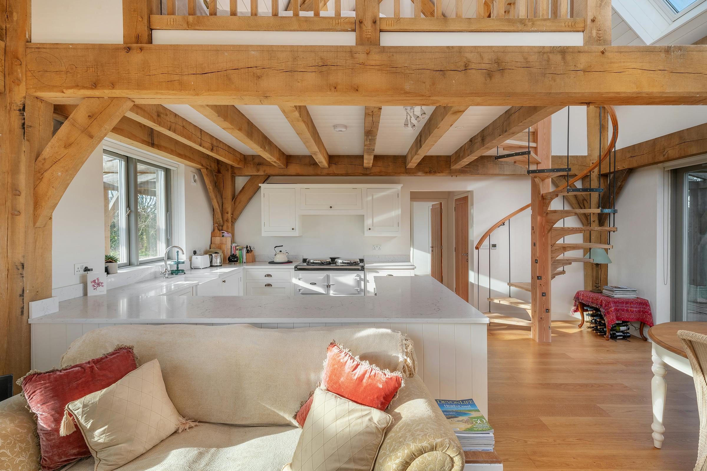 A timber wooden spiral staircase, open plan kitchen and sitting area in an oak framed home