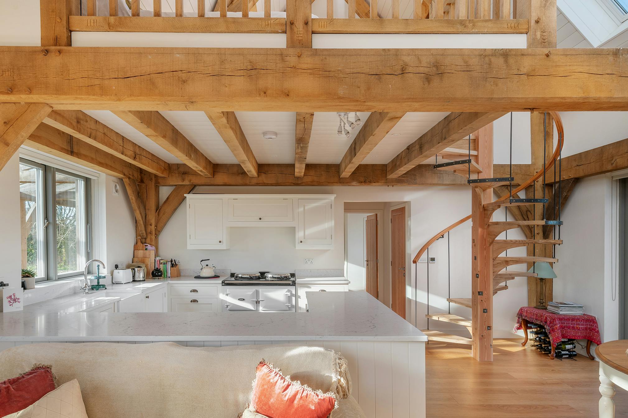 A timber wooden spiral staircase, open plan kitchen and sitting area in an oak framed home