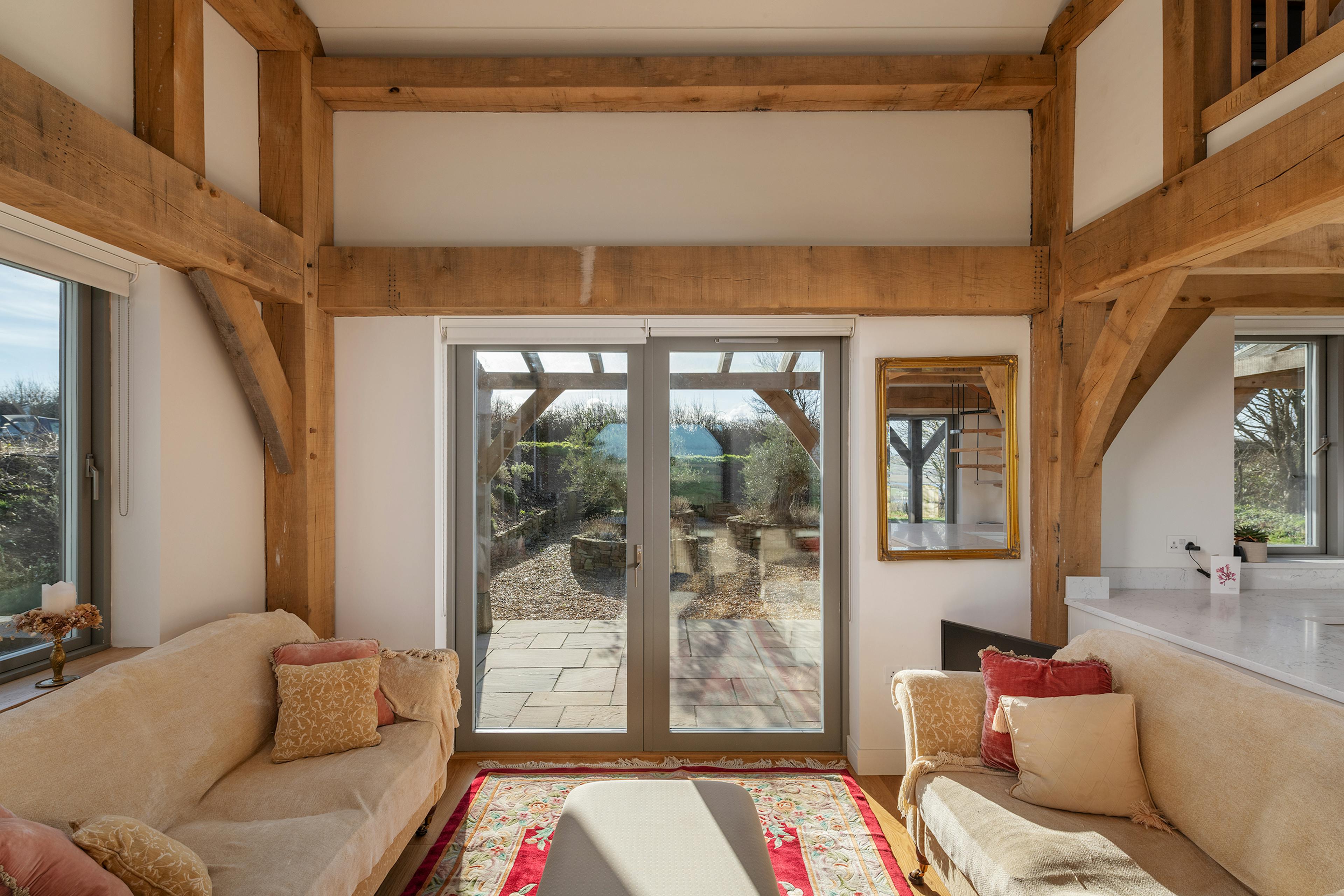 An open sitting area in an oak framed home with doors to a patio and oak framed veranda