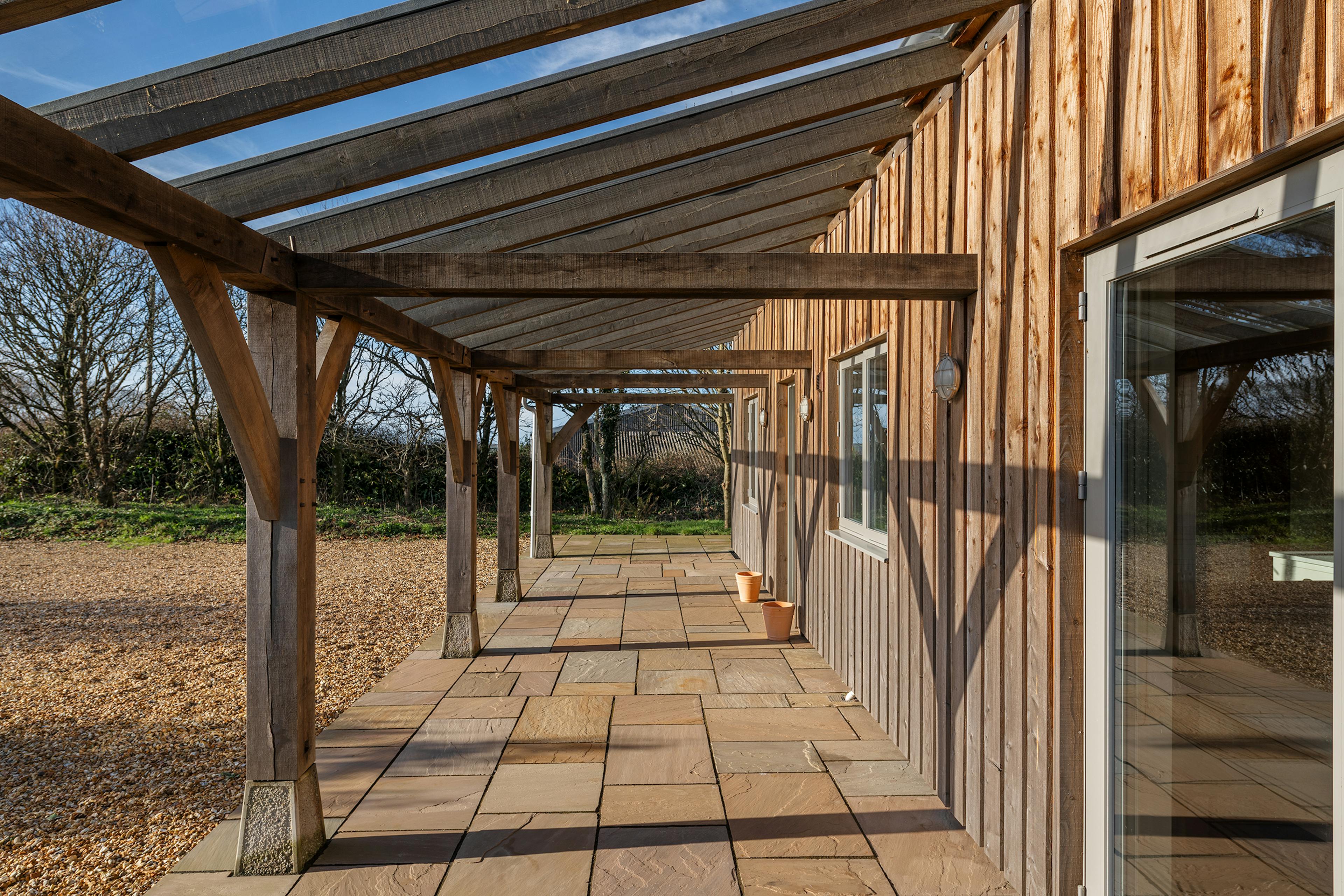A timber clad oak frame home with a glass roofed oak framed veranda
