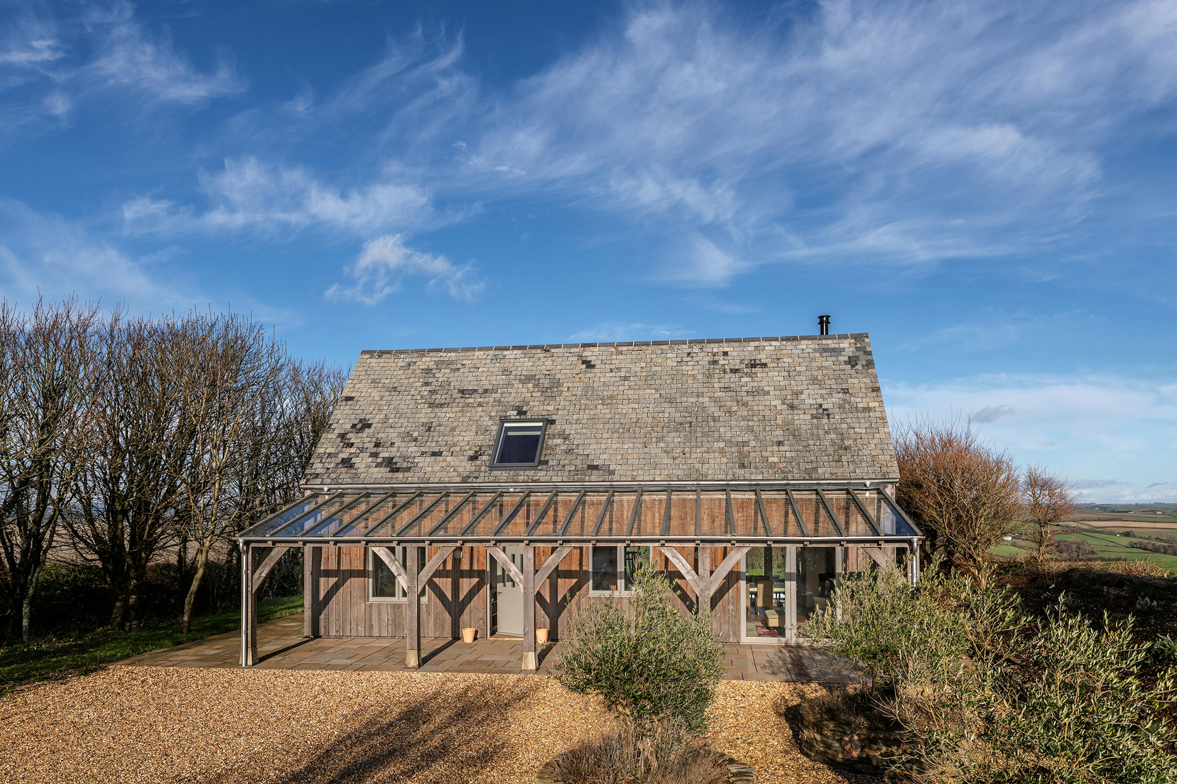 A timber clad oak frame home with a glass roofed oak framed veranda