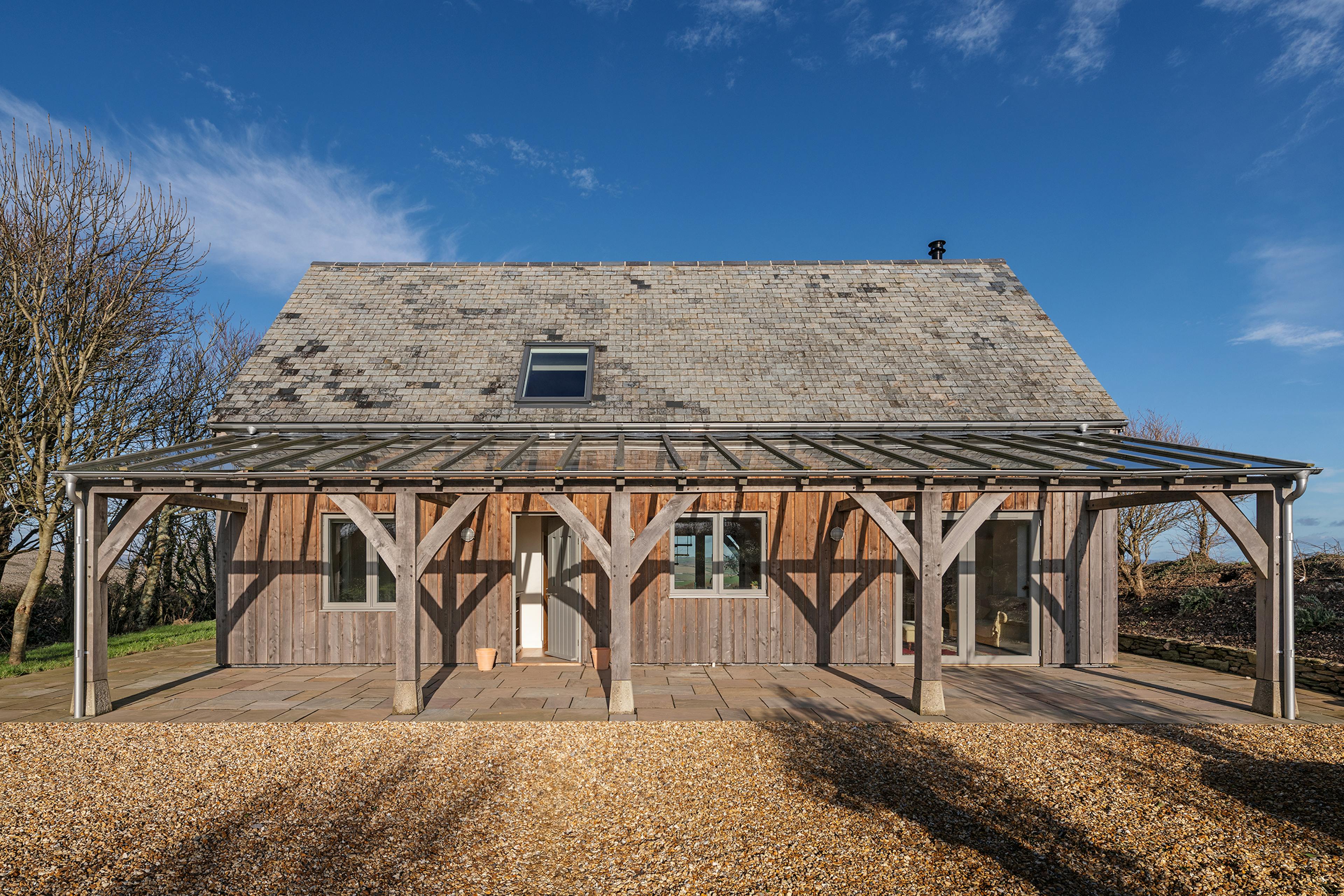 A timber clad oak frame home with a glass roofed oak framed veranda 