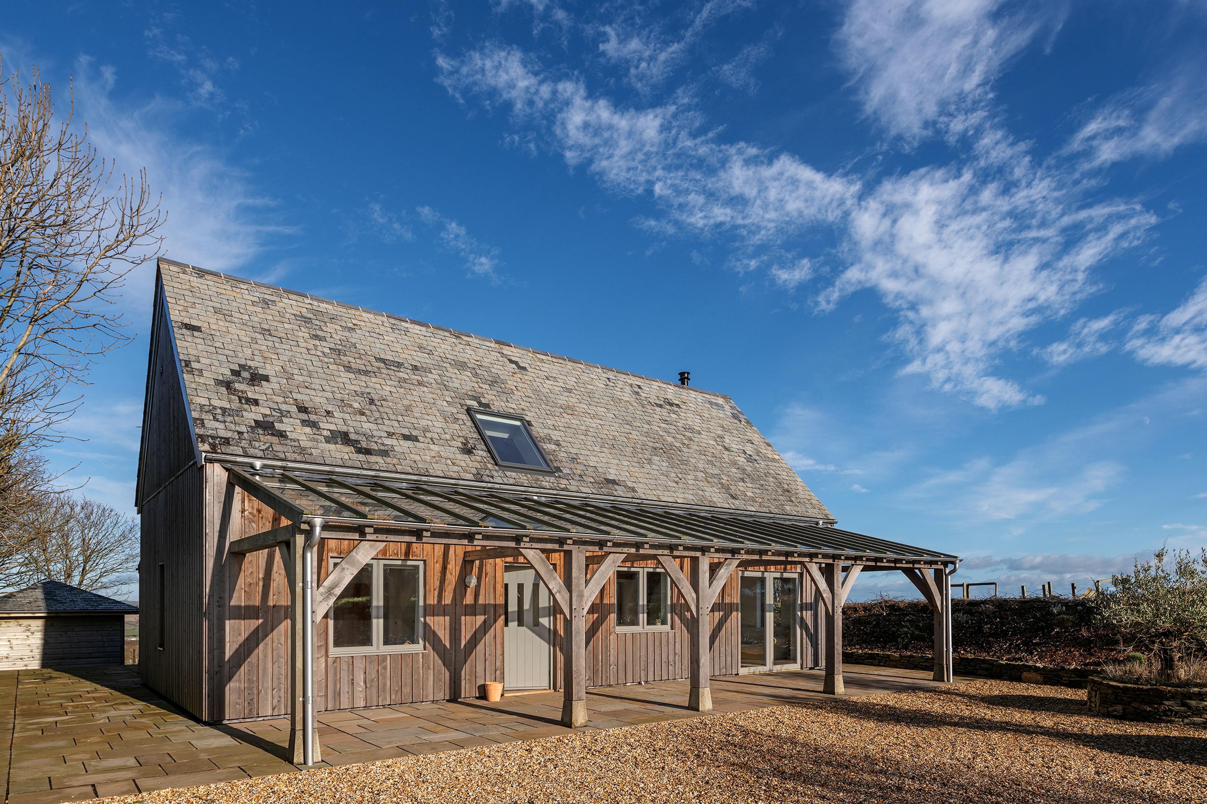 A timber clad oak frame home with a glass roofed oak framed veranda