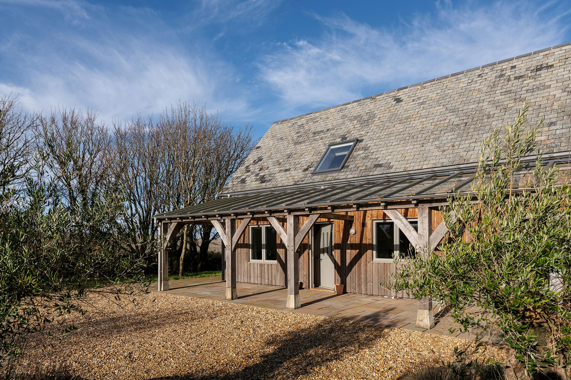 A timber clad oak frame home with a glass roofed oak framed veranda