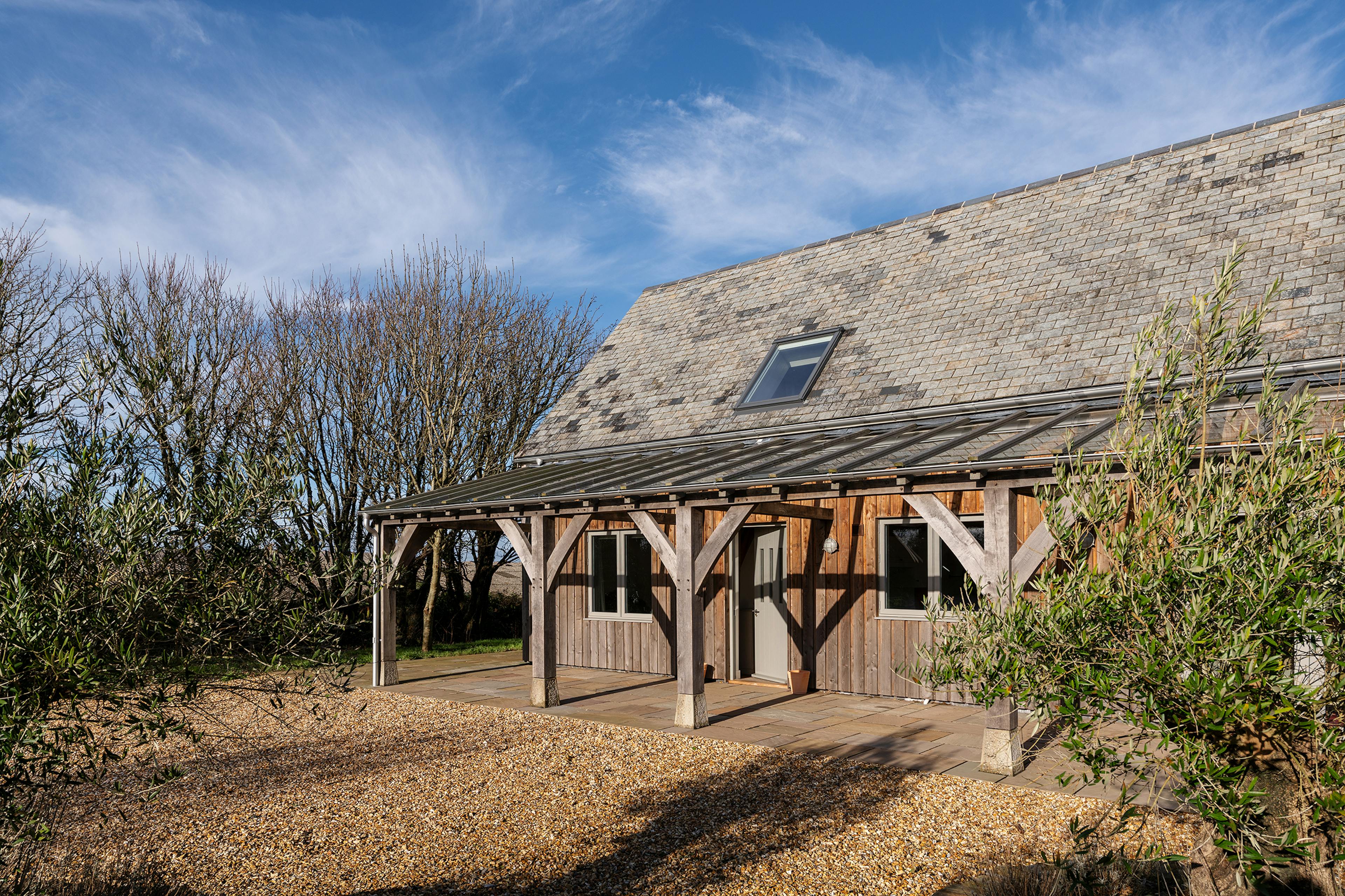 A timber clad oak frame home with a glass roofed oak framed veranda