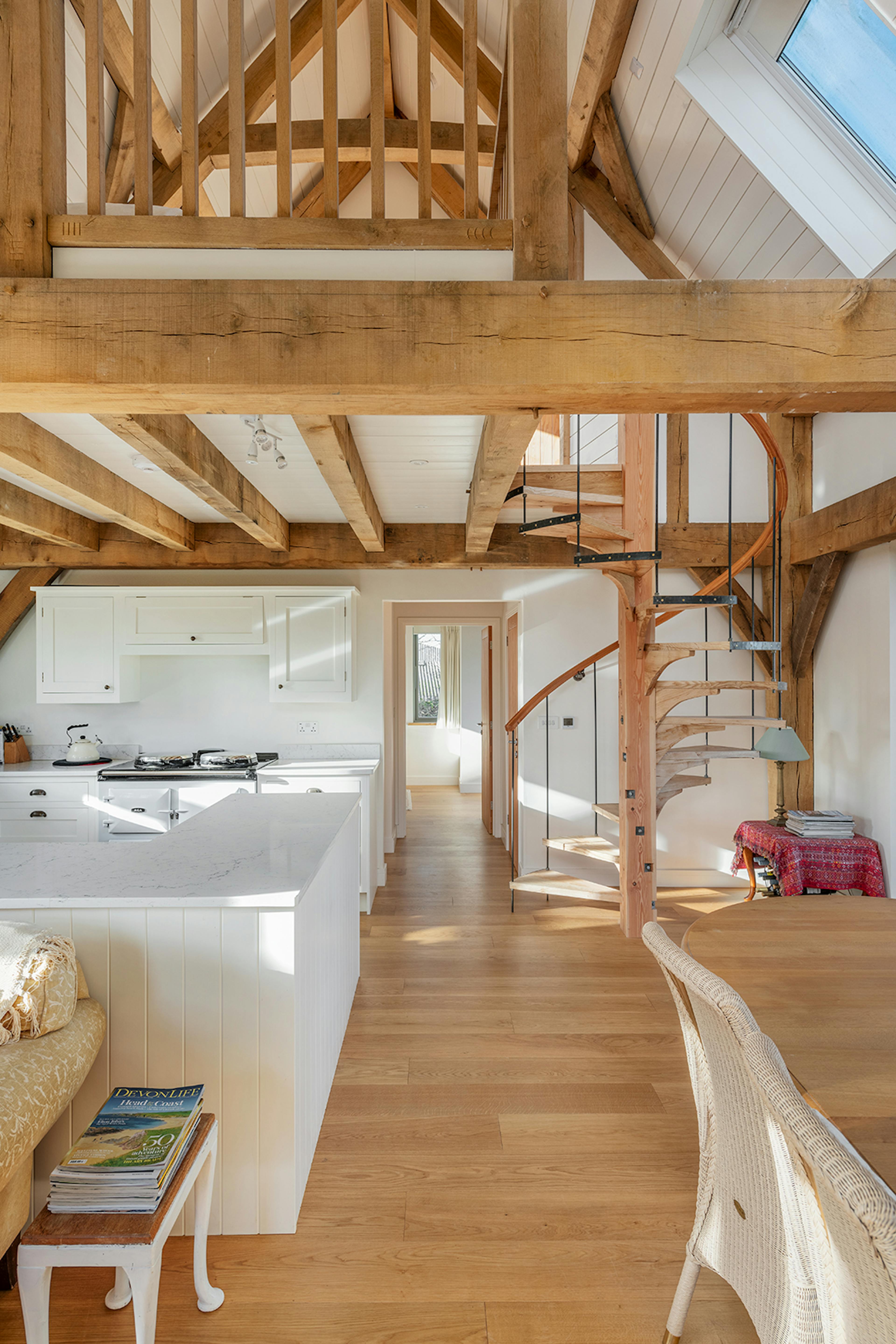 A kitchen and dining area with timber wooden spiral staircase in an oak framed home