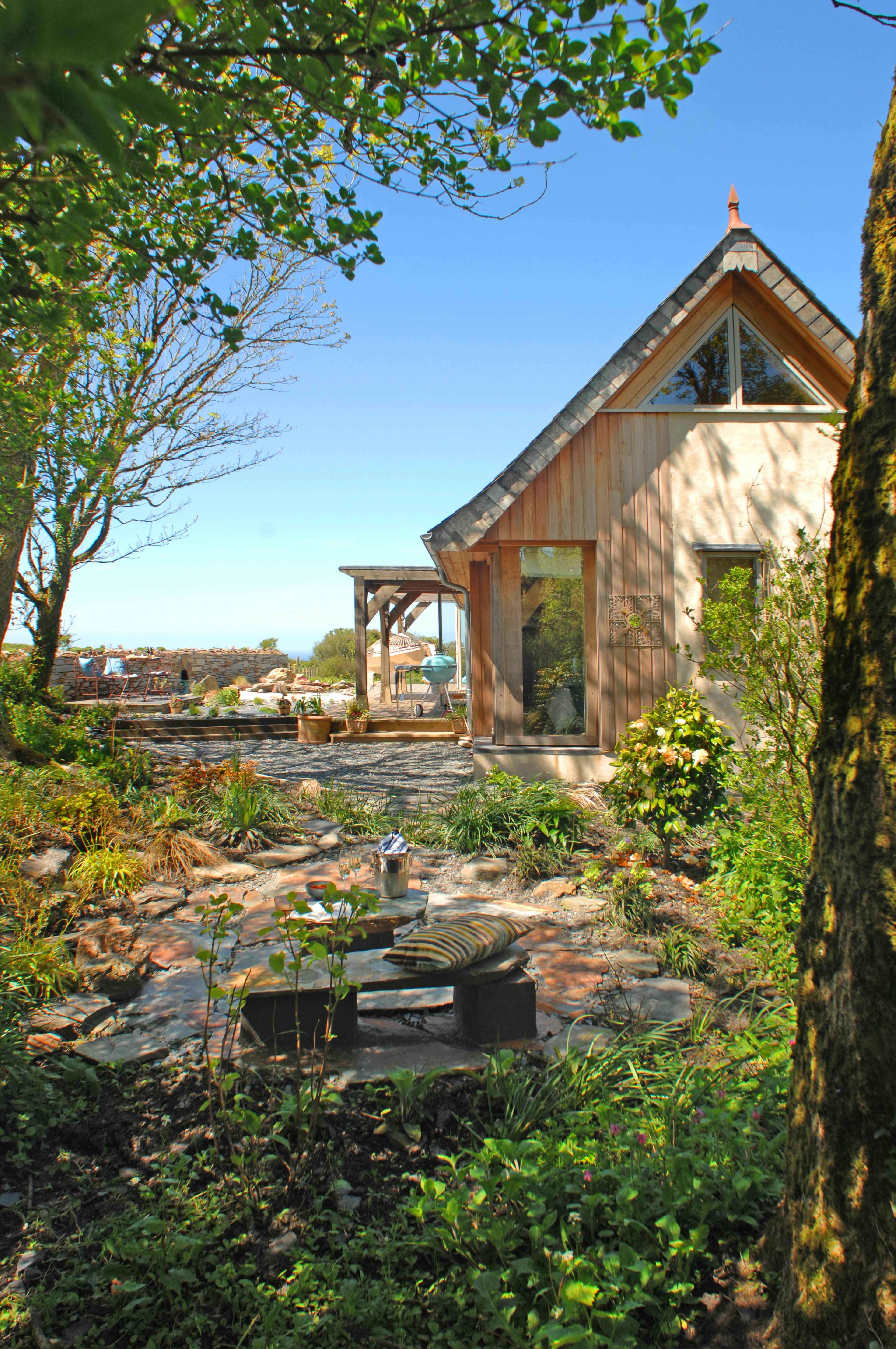 Completed oak-framed house in Cornwall, showcasing a charming exterior and blending seamlessly with its natural retreat setting