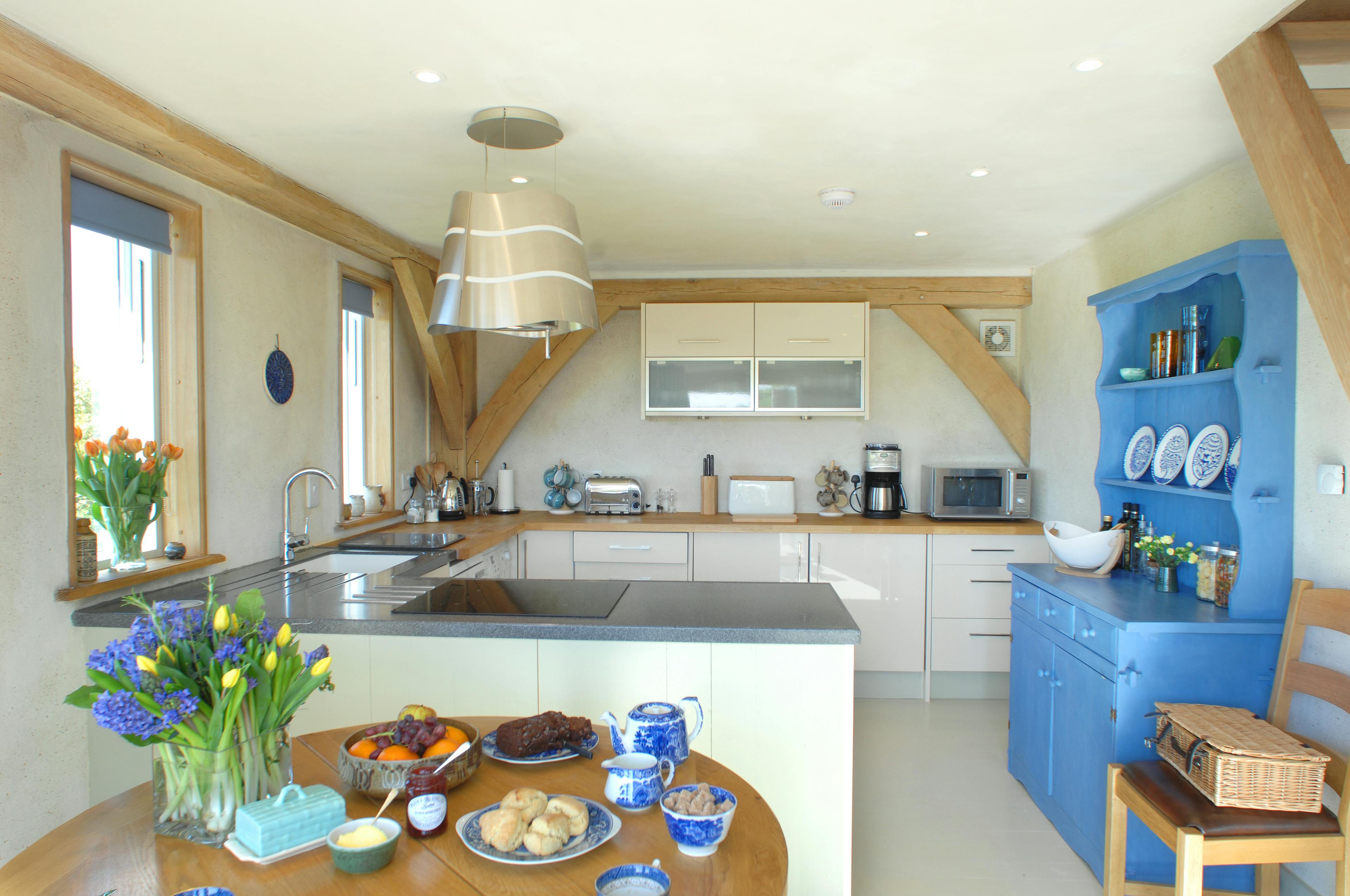 Completed interior of an oak-framed home in Cornwall, highlighting a modern kitchen with natural wood elements and a warm, open design