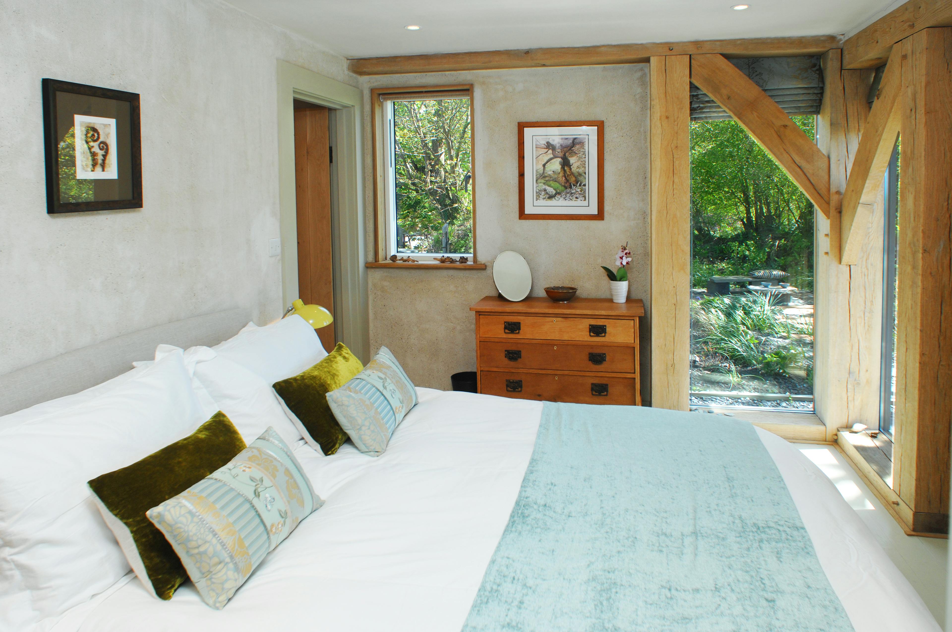 Completed interior of an oak-framed home in Cornwall, featuring a serene bedroom with natural wood finishes and a cozy, inviting atmosphere